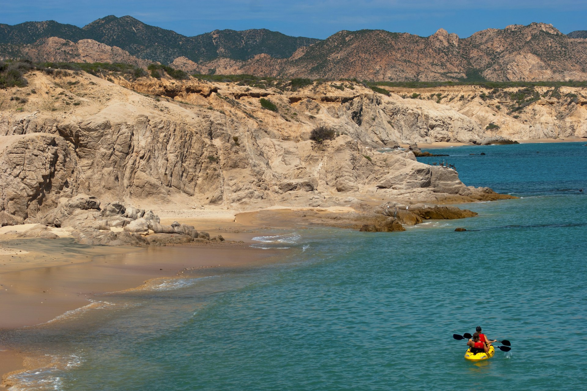 Kayak padding on the sea with the desert on the horizon