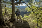 A hiker pauses at a lookout point over a tree-covered valley on the Appalachian Trail in Georgia.