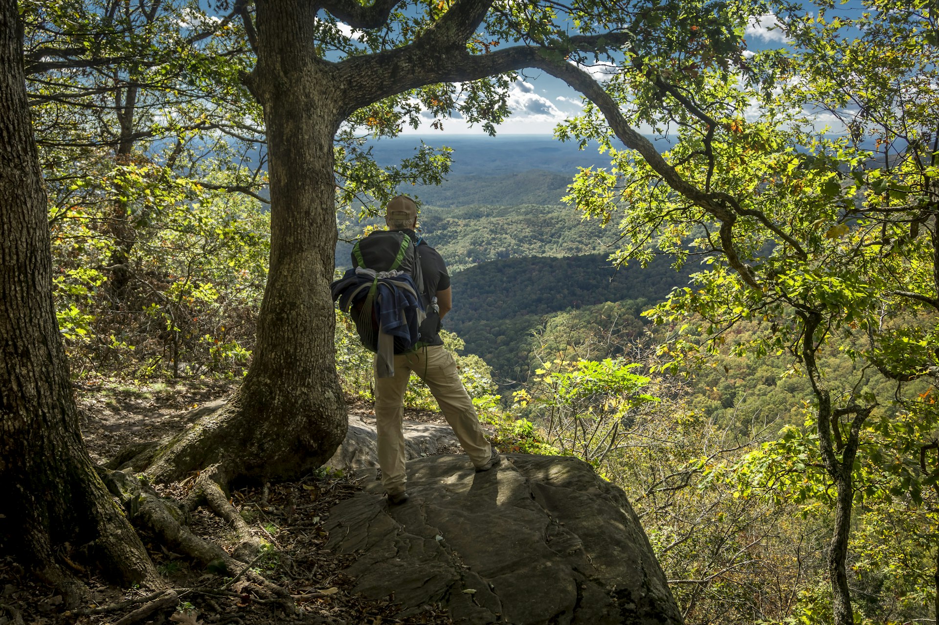 A hiker pauses at a lookout point over a tree-covered valley on the Appalachian Trail in Georgia