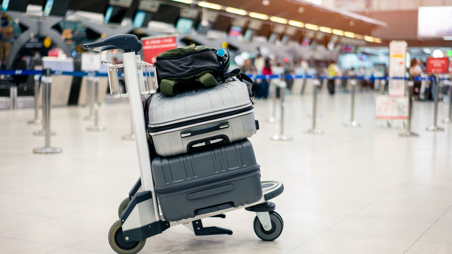 Suitcases stacked on a luggage trolley in an international airport.