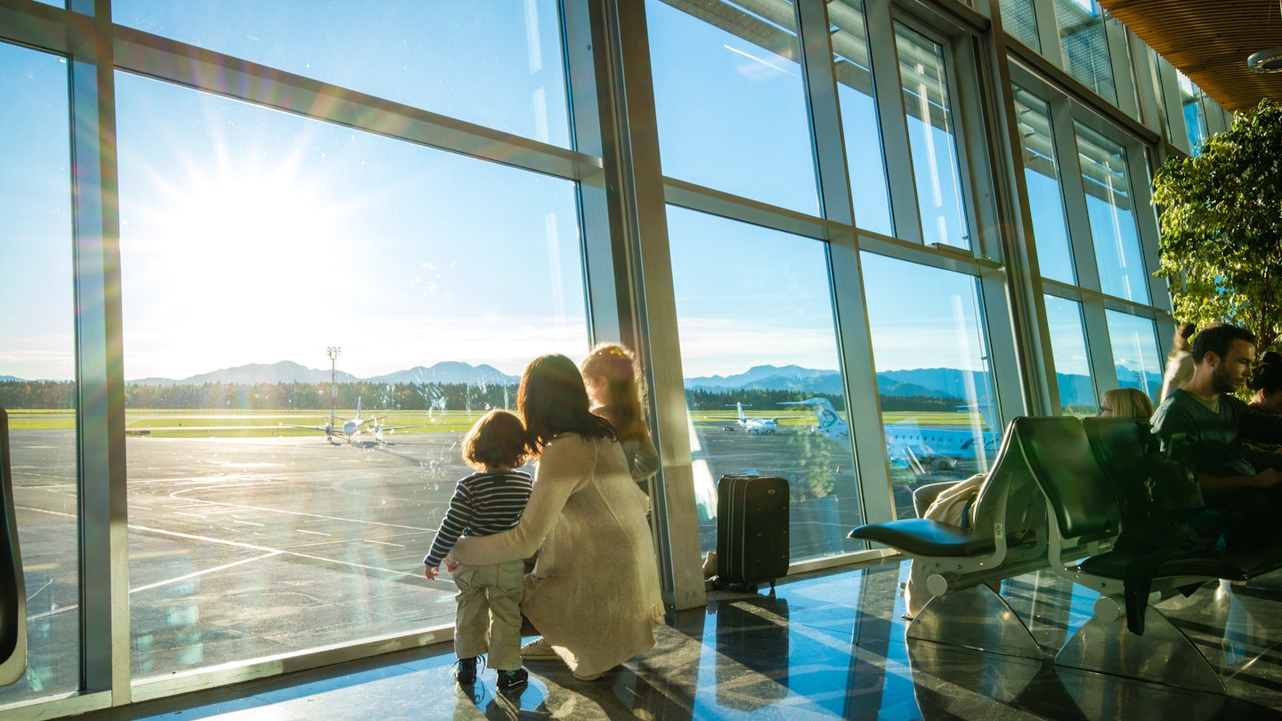 Mother and children looking through window in airport.