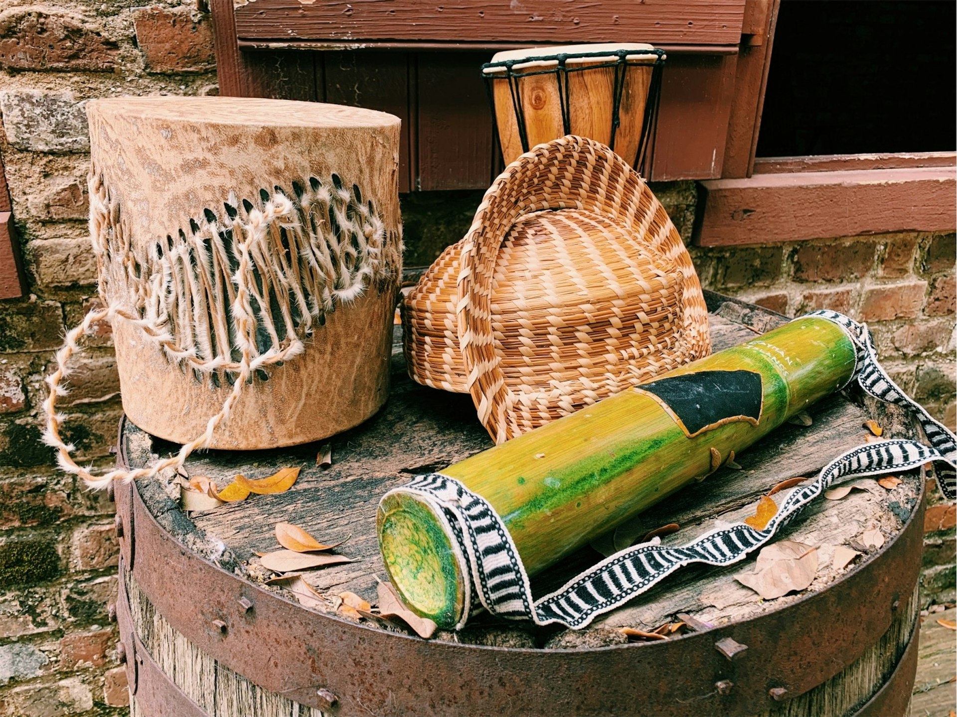 A trio of historic Gullah pieces sit on a wooden barrell. 