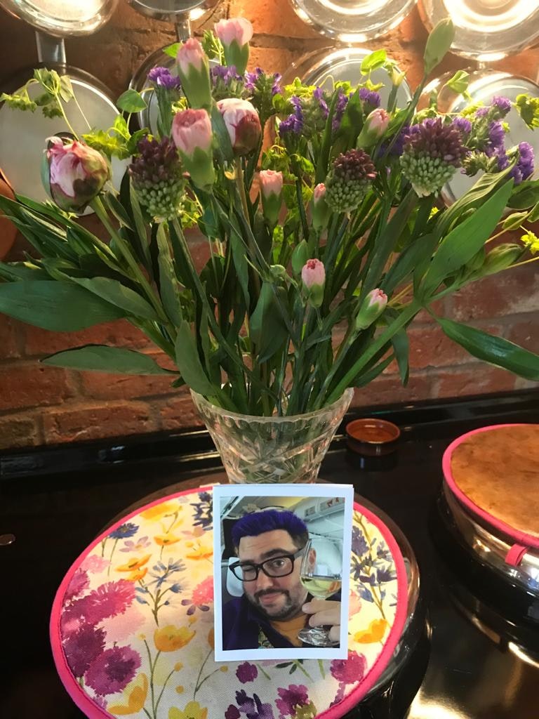 A bouquet of flowers next to a printed image of a man holding a glass of wine