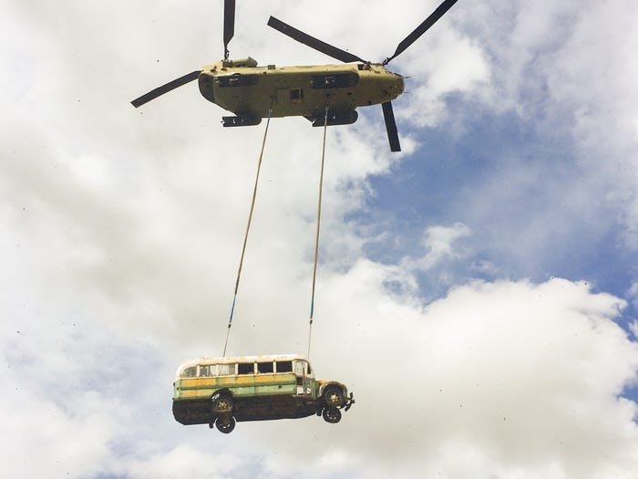 A heliopter lifting the Into the Wild Bus to the skies