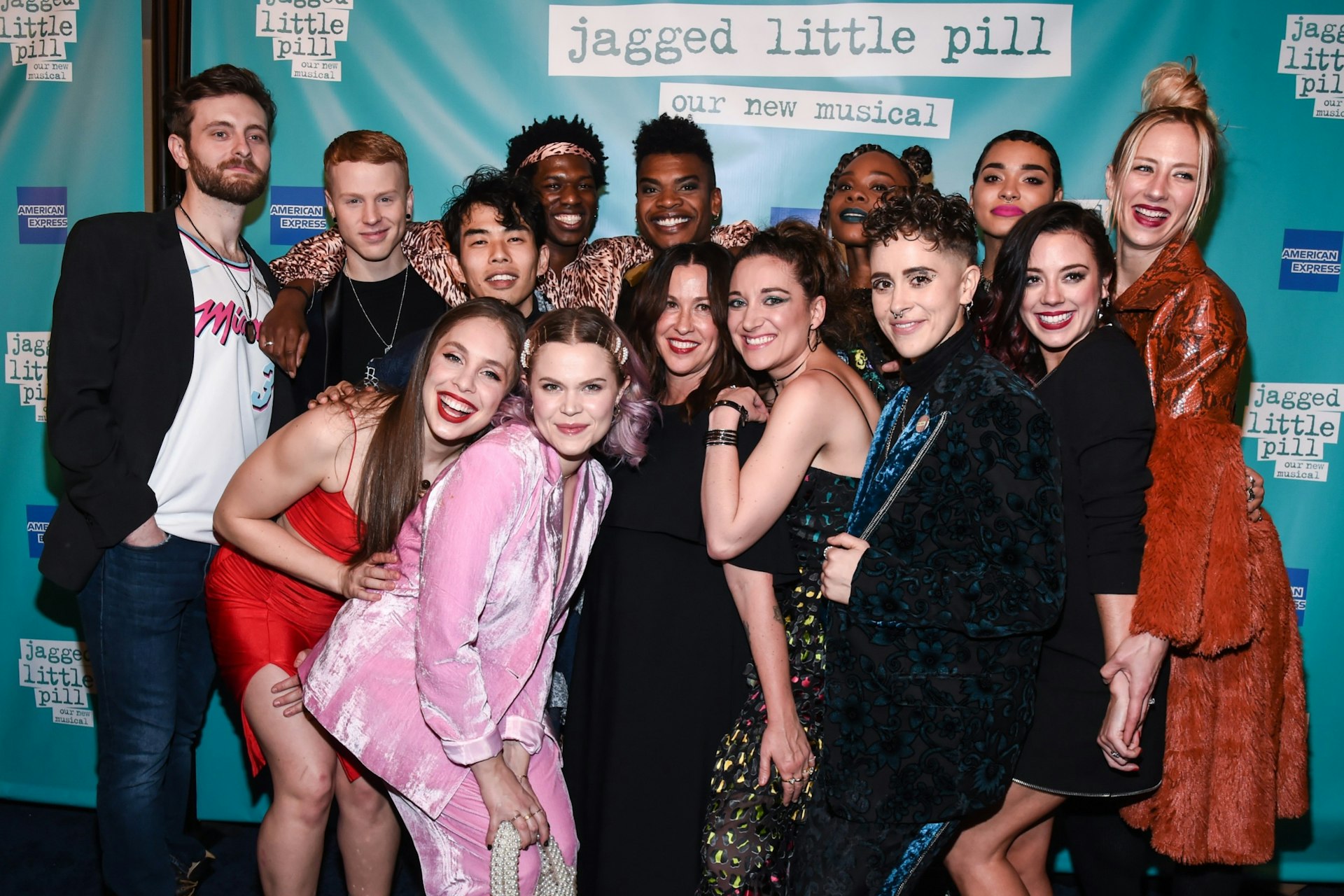 Singer Alanis Morisette with the cast of "Jagged Little Pill" in front of a photo backdrop