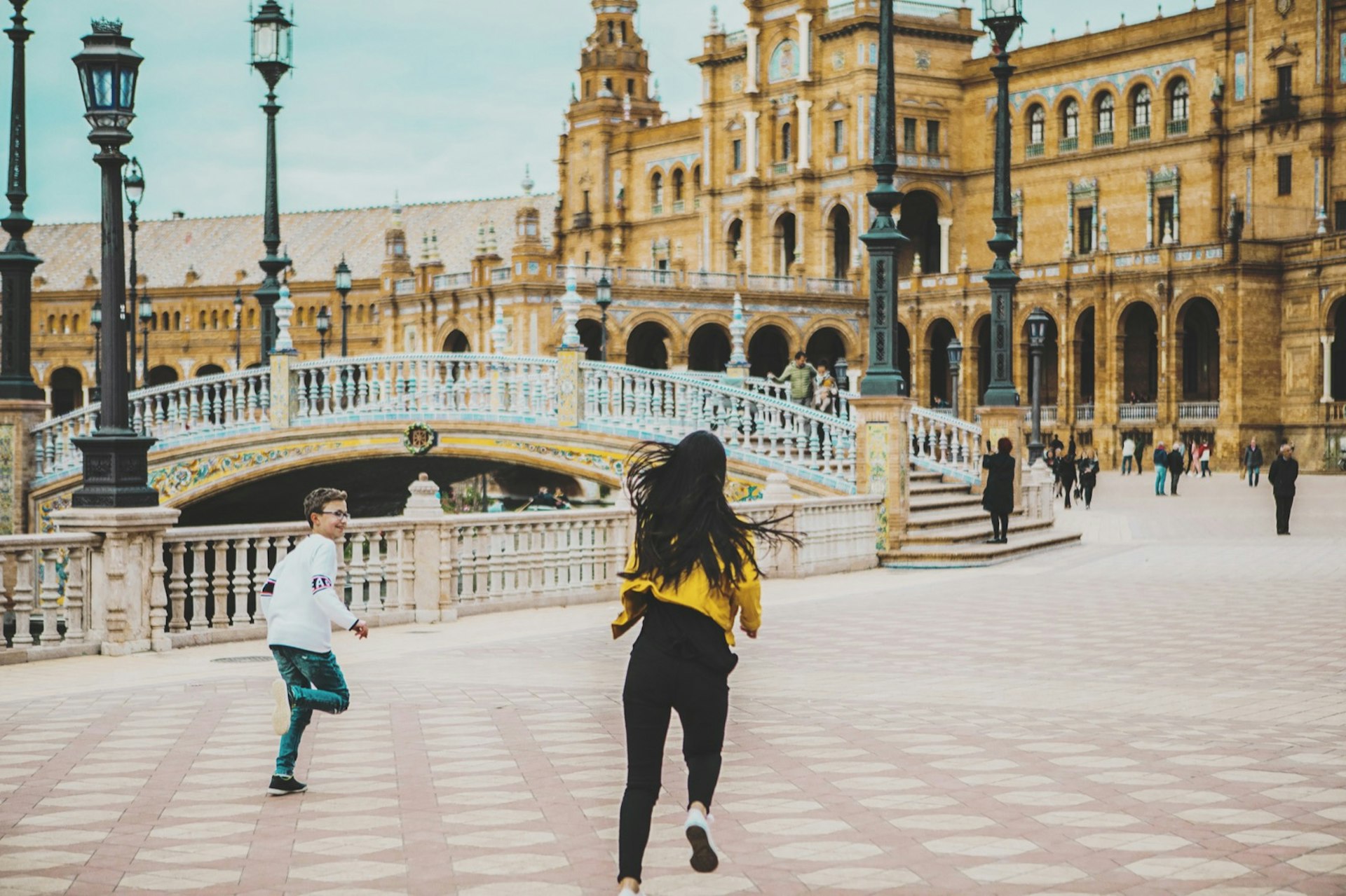 two sibling running across España square,Seville, Spain