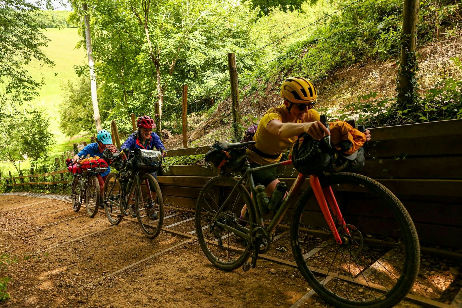 Three cyclists push their bikes up an unrideable section of the Thames Path