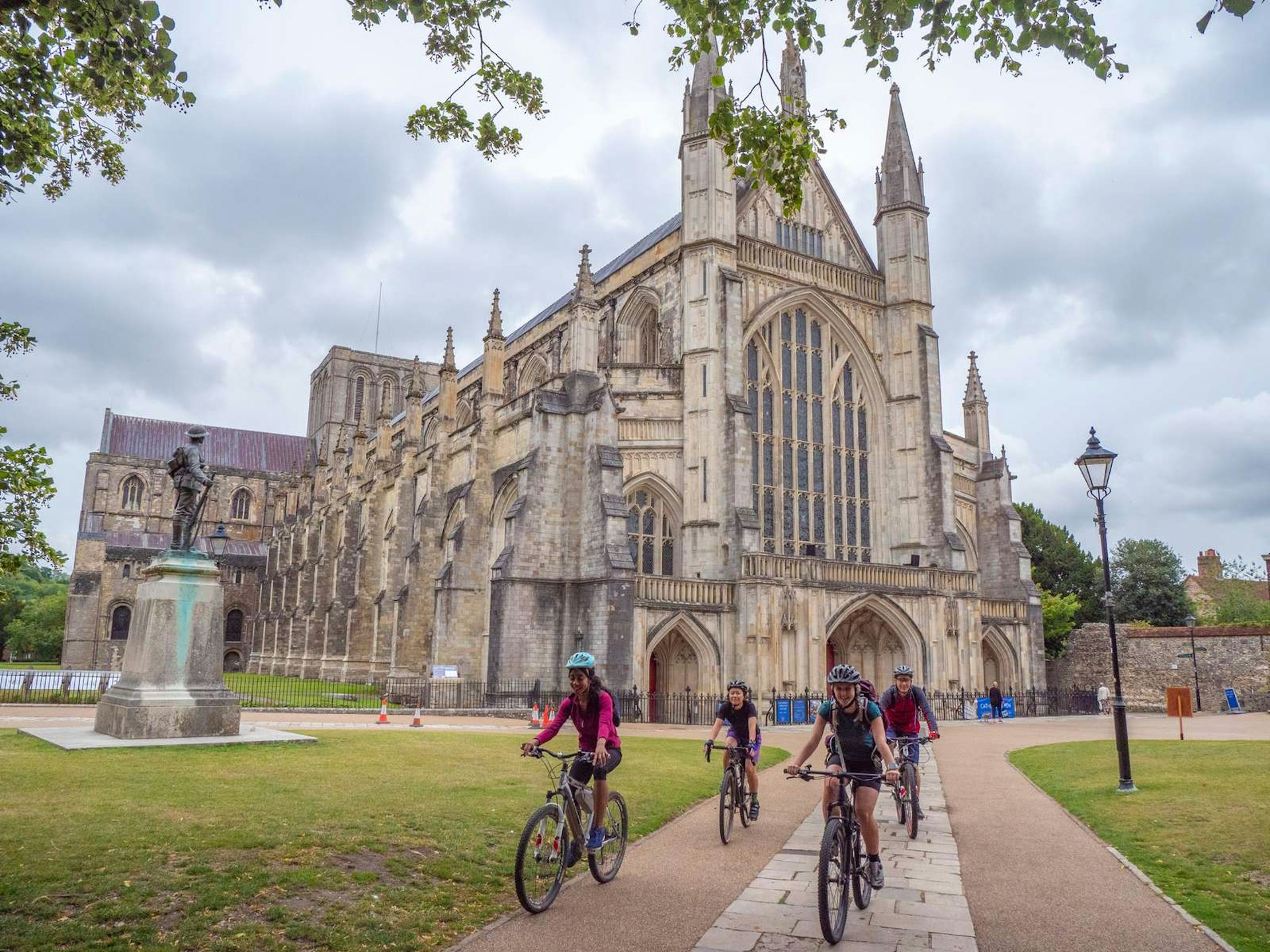 Four people cycle past Winchester Cathedral