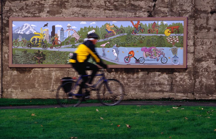 en cyklist som passerar framför en väggmålning i Seattle