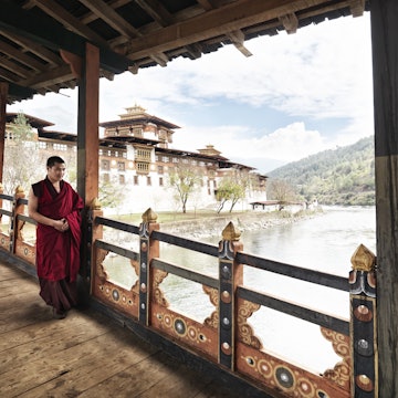 Monk walking on balcony at Punakha Dzong on junction of Pho Chhu and Mo Chhu rivers.