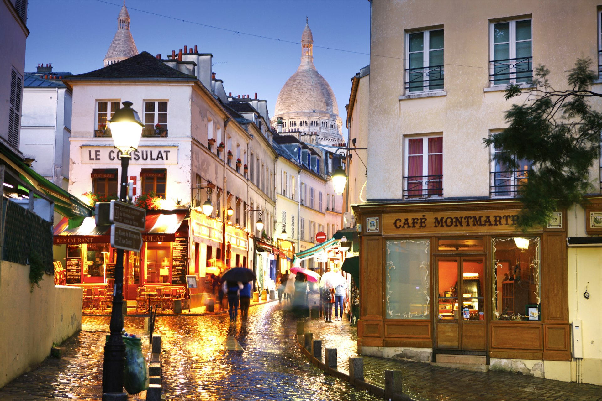 A Parisian street scene, with the Dome of Sacre Coeur de Montmartre in the background