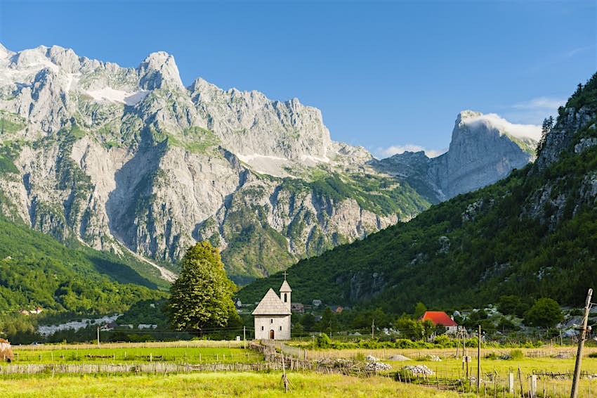 Një kishë e vendosur në një luginë mali nën një qiell blu