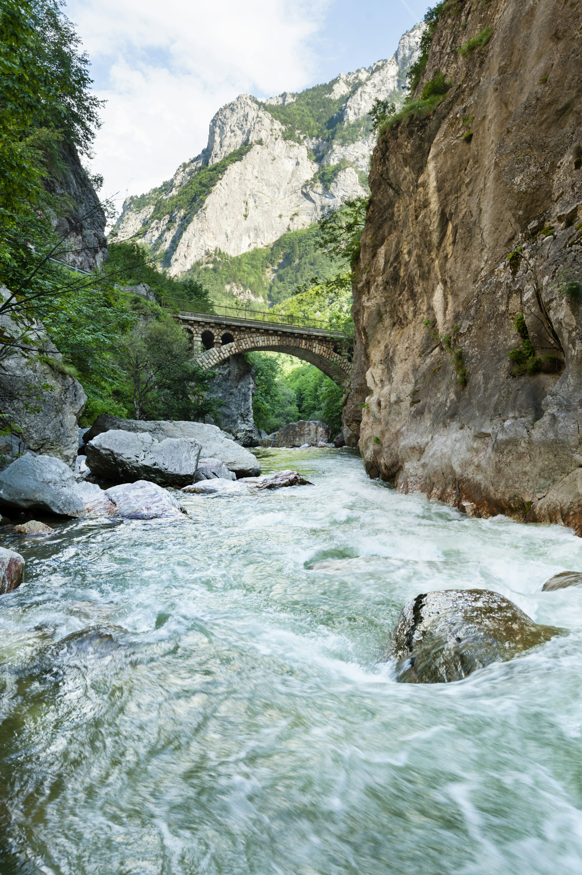 An old bridge over a canyon with rushing water below