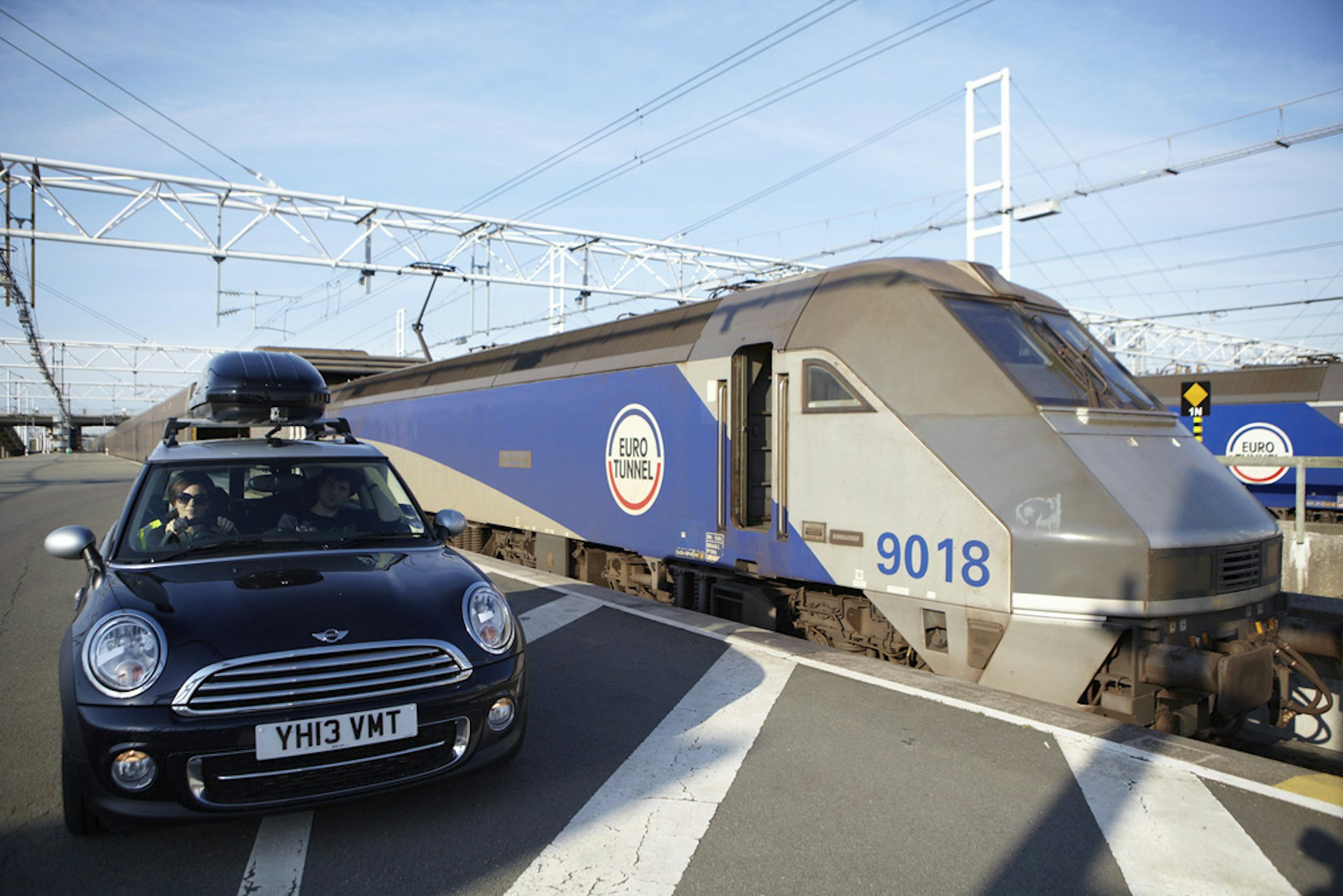 A dark colored Mini parked by the front of a Eurotunnel train 