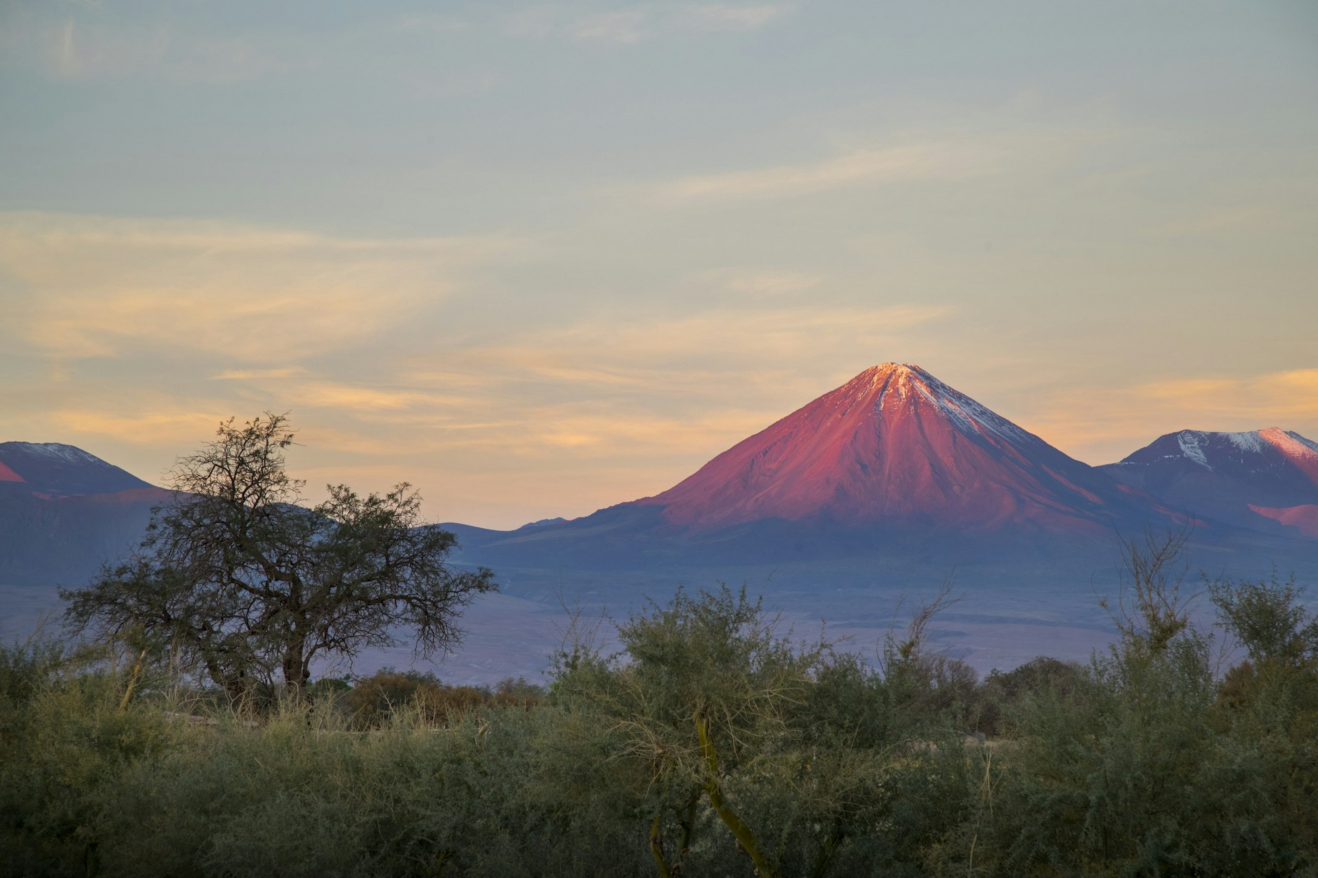 A perfectly triangular mountain peak reflects the setting sun