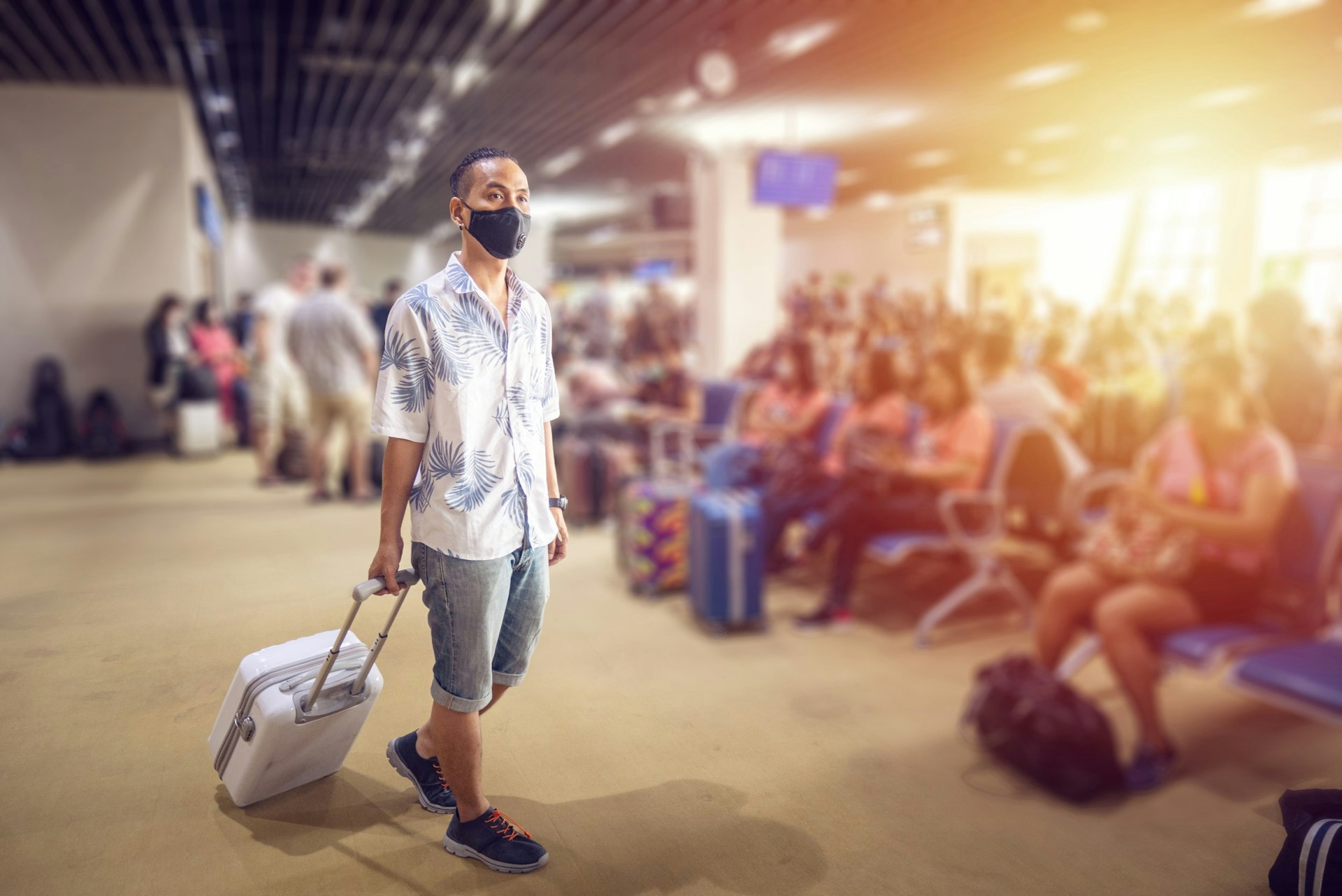 A man wearing a face mask walking through the airport