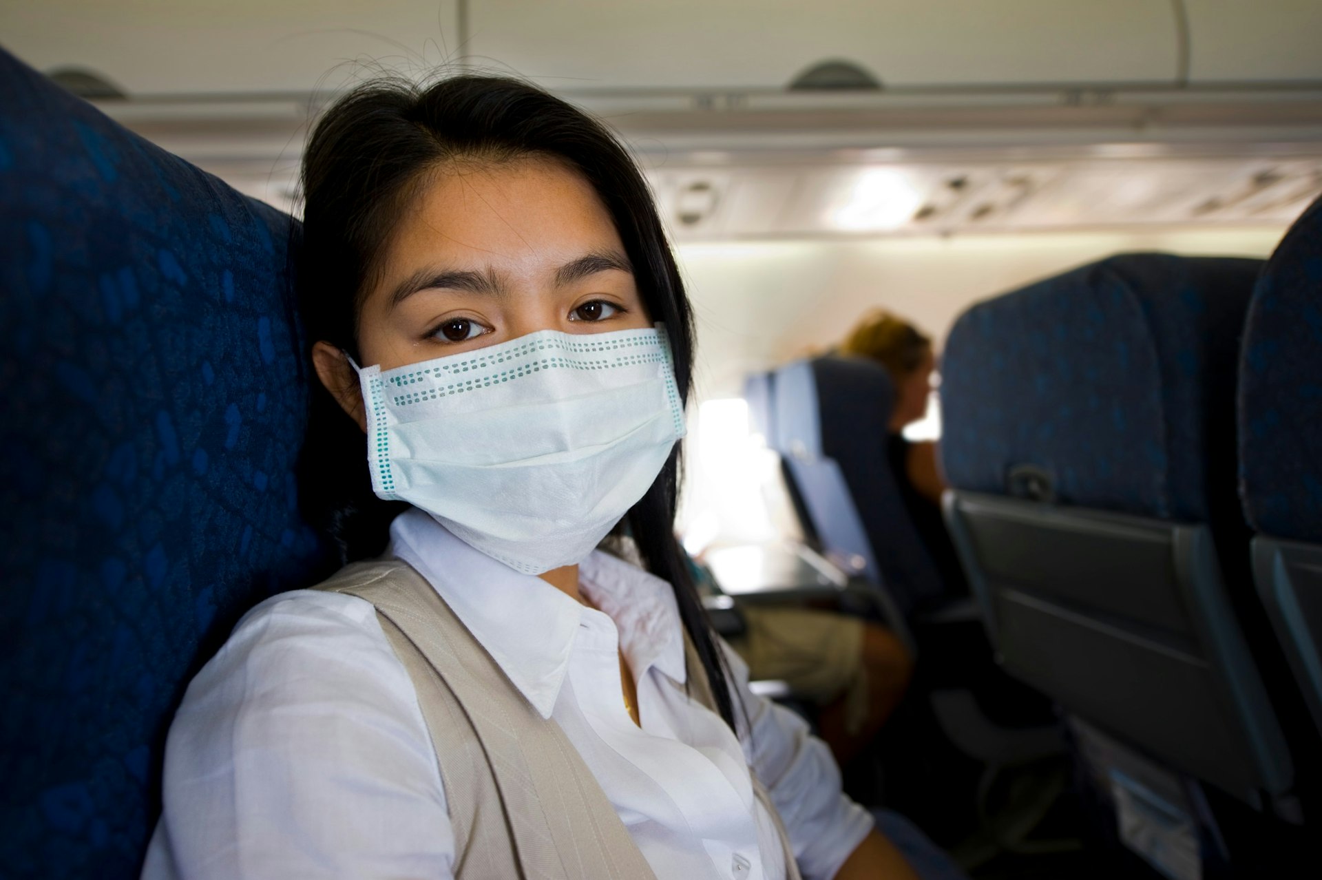 A woman wearing a mask on a plane