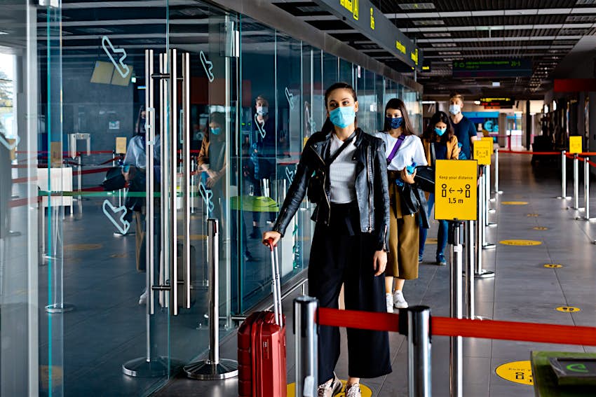 Passengers wearing N95 face masks waiting in line at airport terminal
