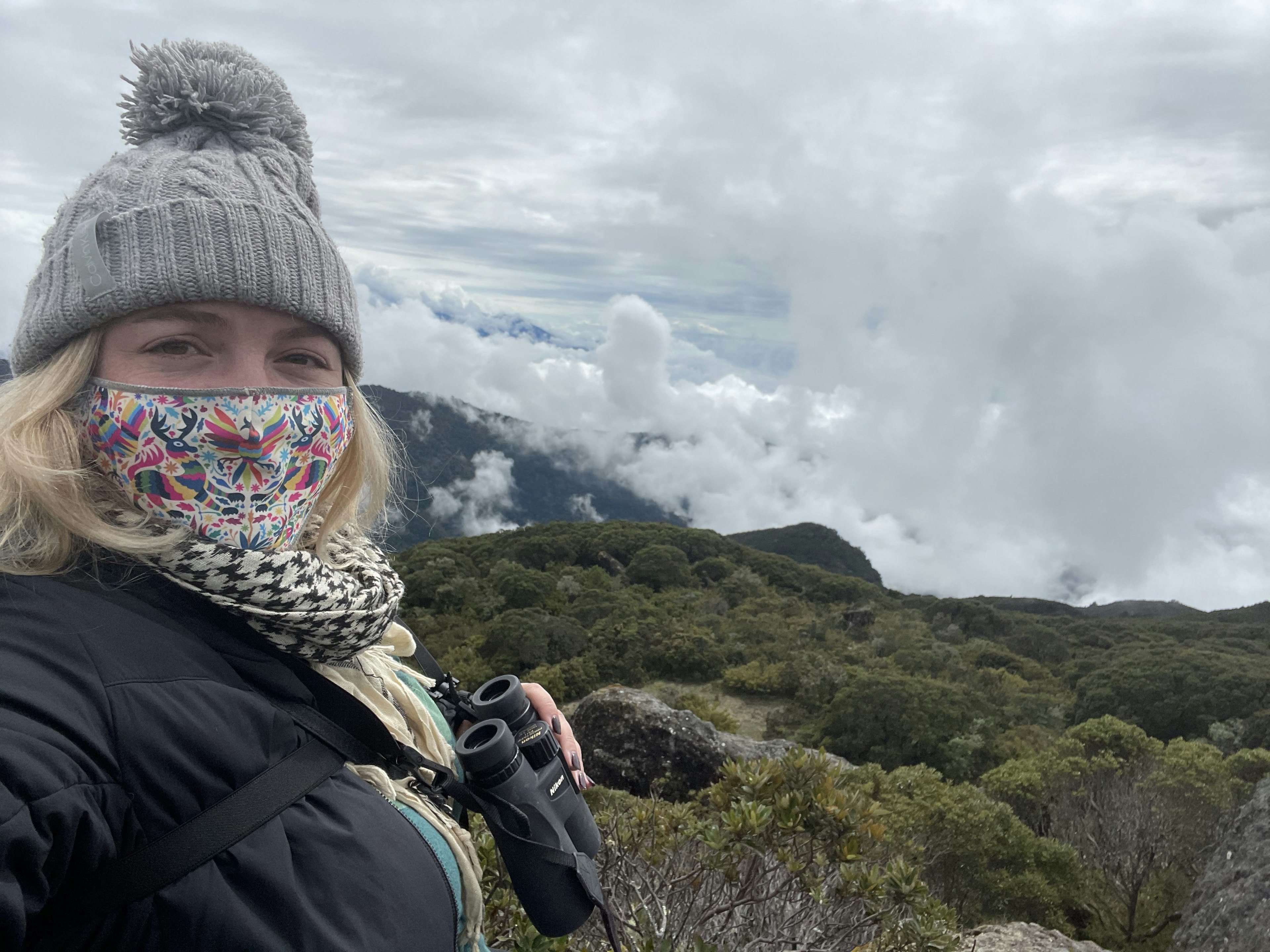 Masked woman taking a selfie while holding a pair of binoculars