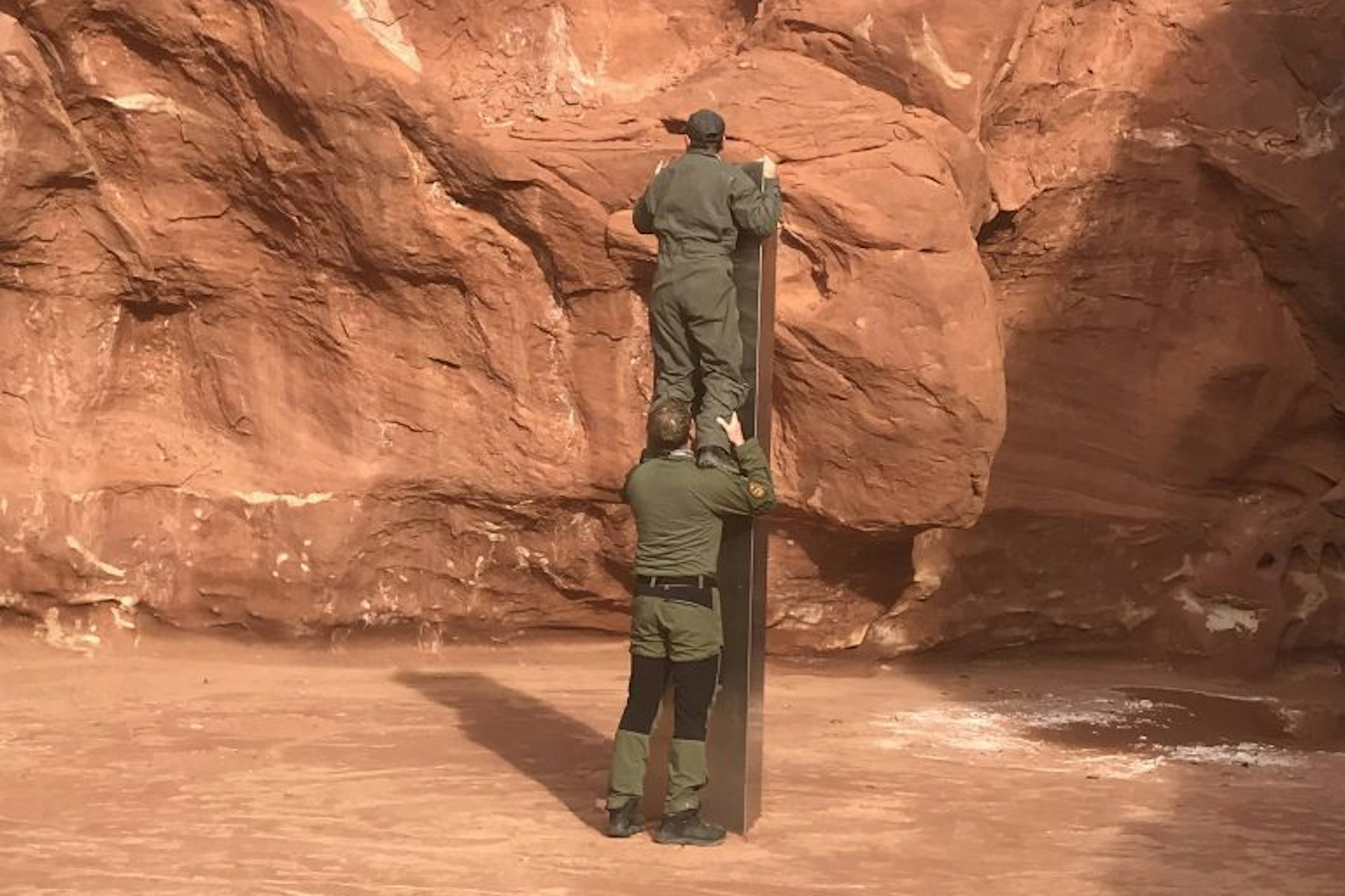 Two men examining a metal monolith found in Utah