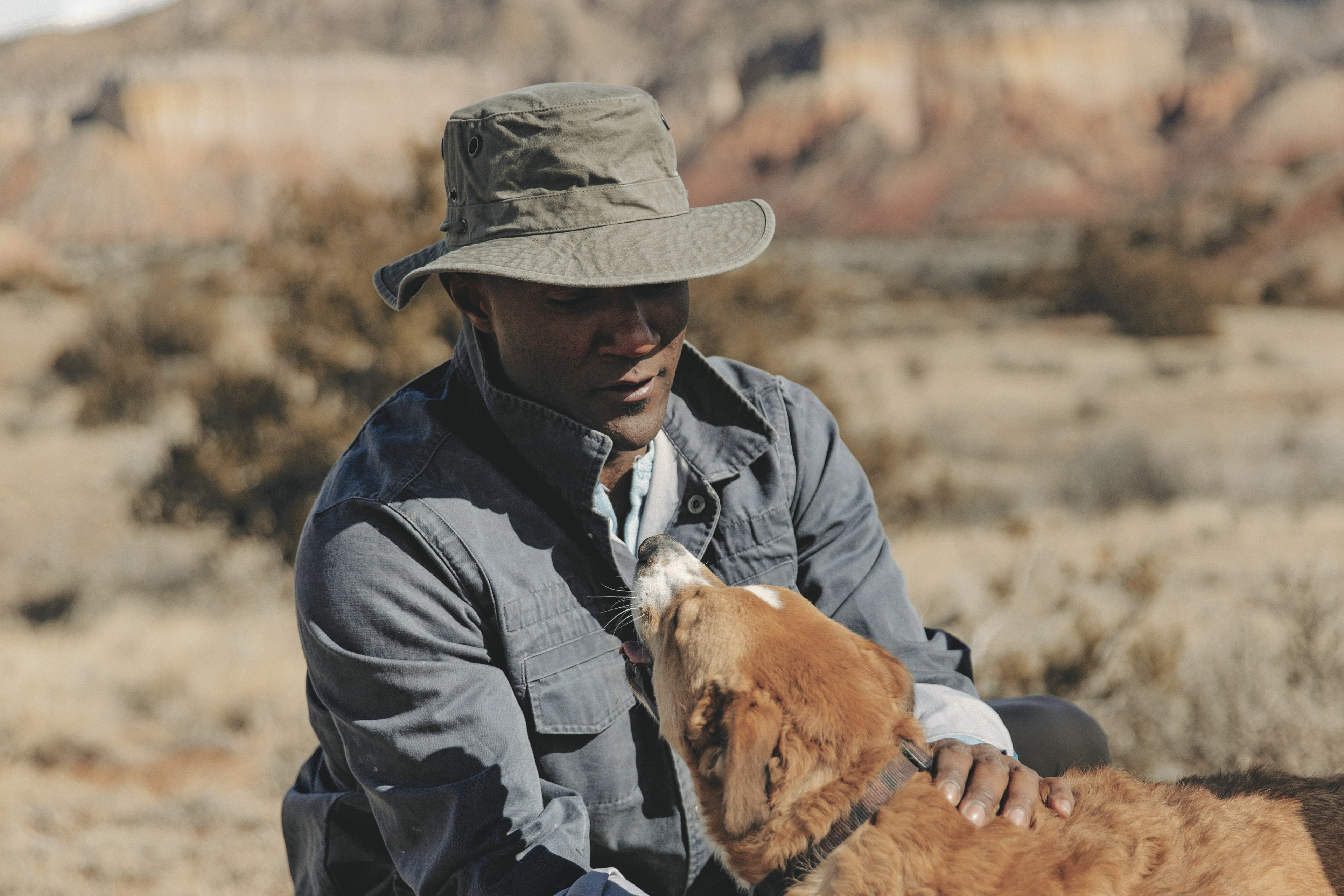 man in a bucket hat petting a dog