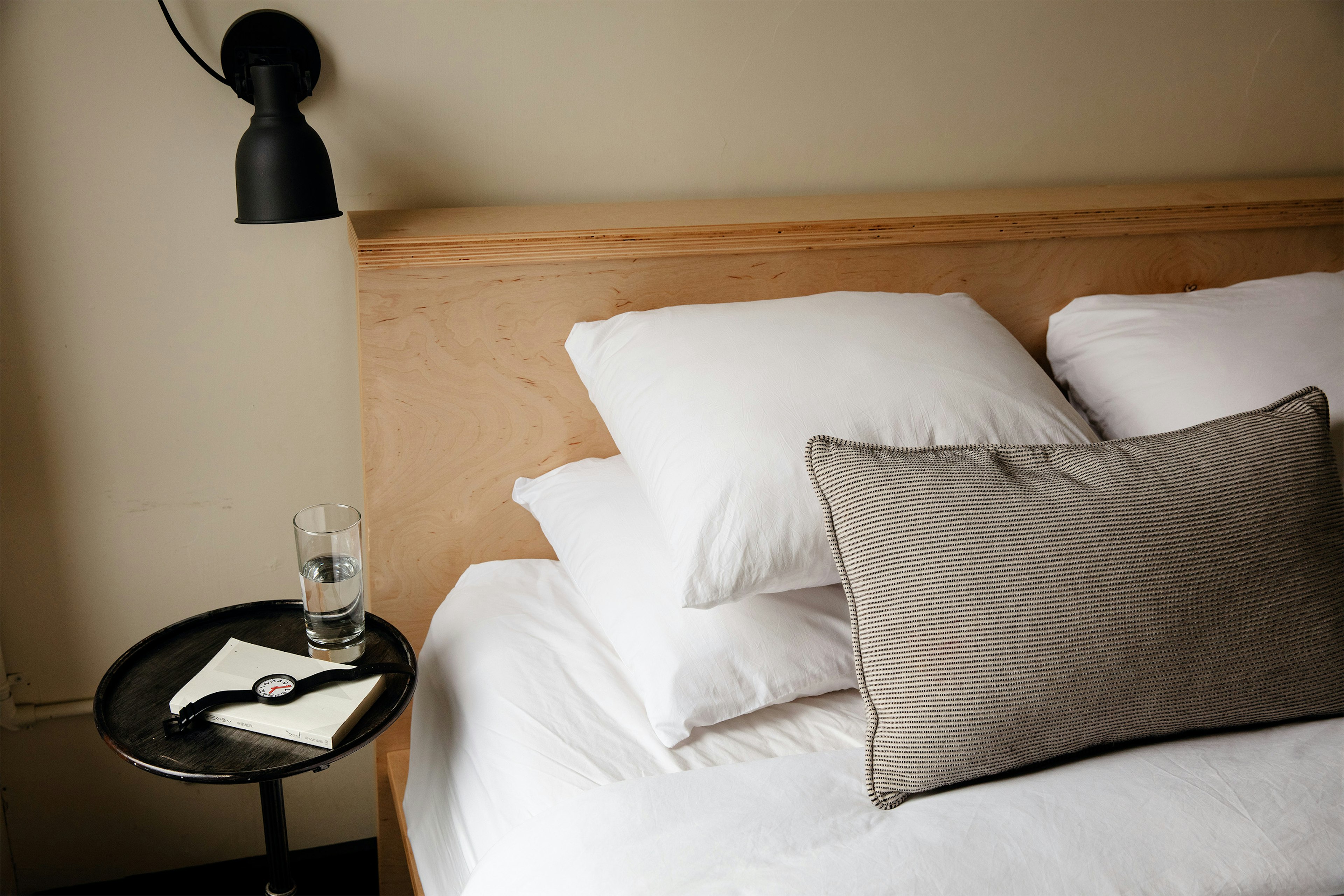 A bed with white linens and a glass of water on the nightstand