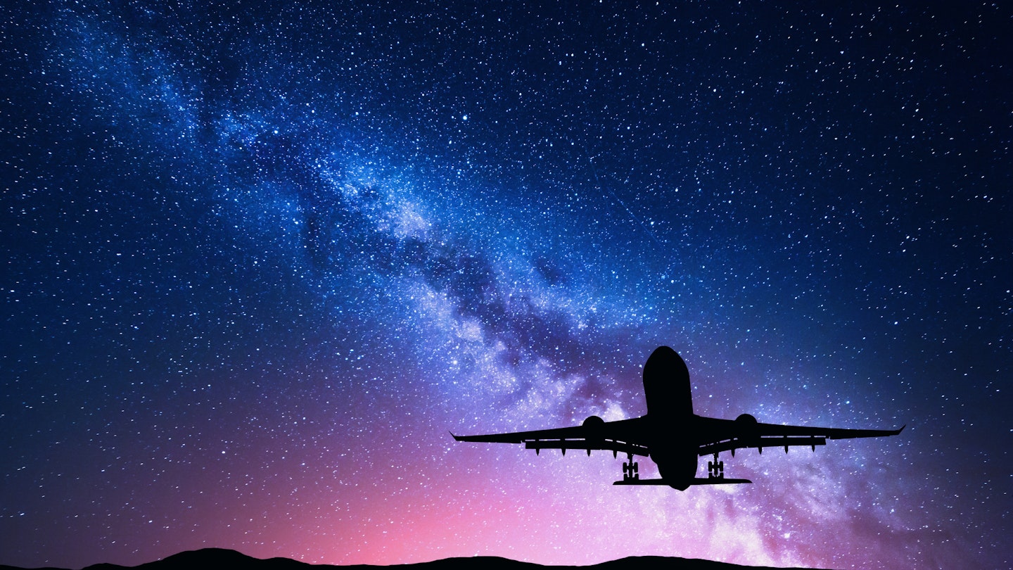 Milky Way and silhouette of a airplane. Landscape with passenger airplane is flying in the starry sky at night. Space background. Landing airliner on the background of colorful Milky Way. Aircraft