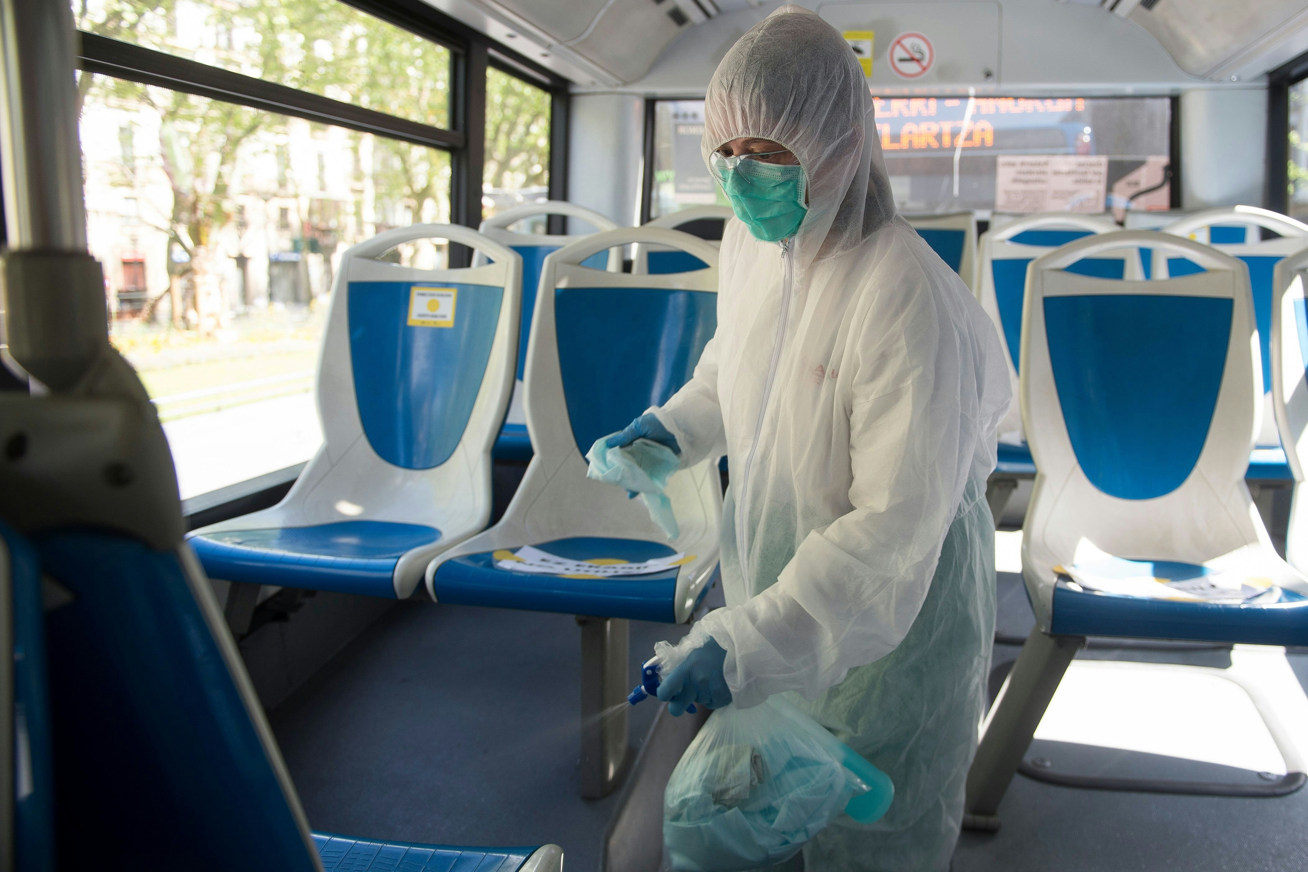 An employee wearing PPE cleans a public bus in Spain