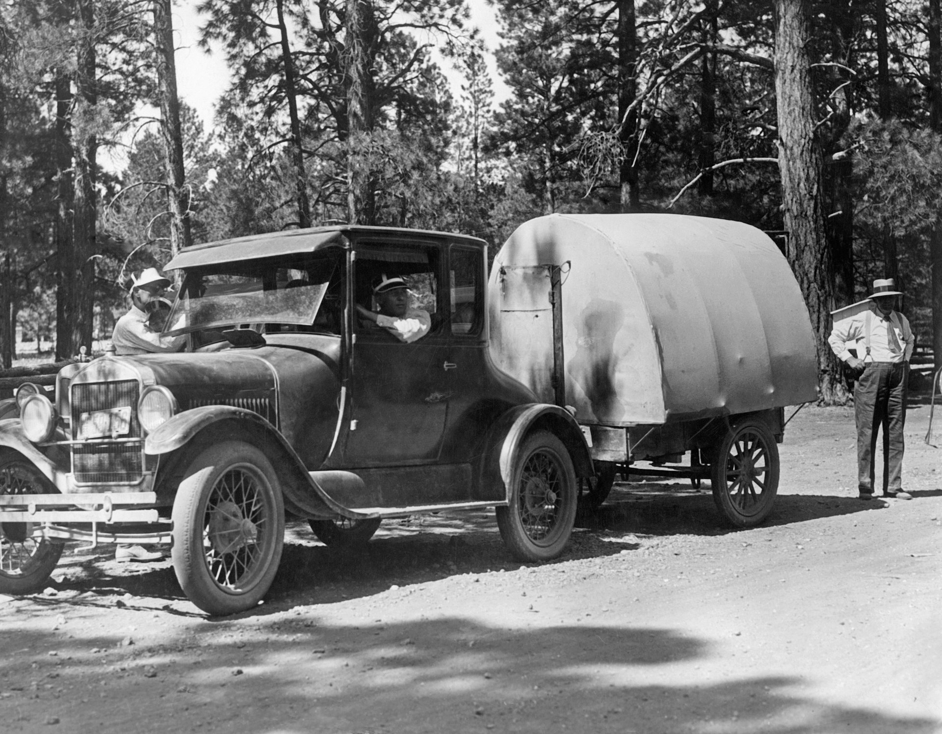 A car pulls an early caravan with tent construction in the Kaibab National Forest on the northern edge of the Grand Canyon.
