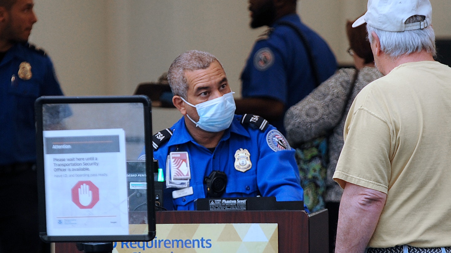 ORLANDO, FLORIDA, UNITED STATES - APRIL 2, 2020: A TSA officer wears a protective mask while screening travellers at Orlando International Airport. In the past 14 days across the nation, 58 TSA screening officers have tested positive for COVID-19, including 9 in Orlando.- PHOTOGRAPH BY Paul Hennessy / Echoes Wire/ Barcroft Studios / Future Publishing (Photo credit should read Paul Hennessy / Echoes Wire/Barcroft Media via Getty Images)