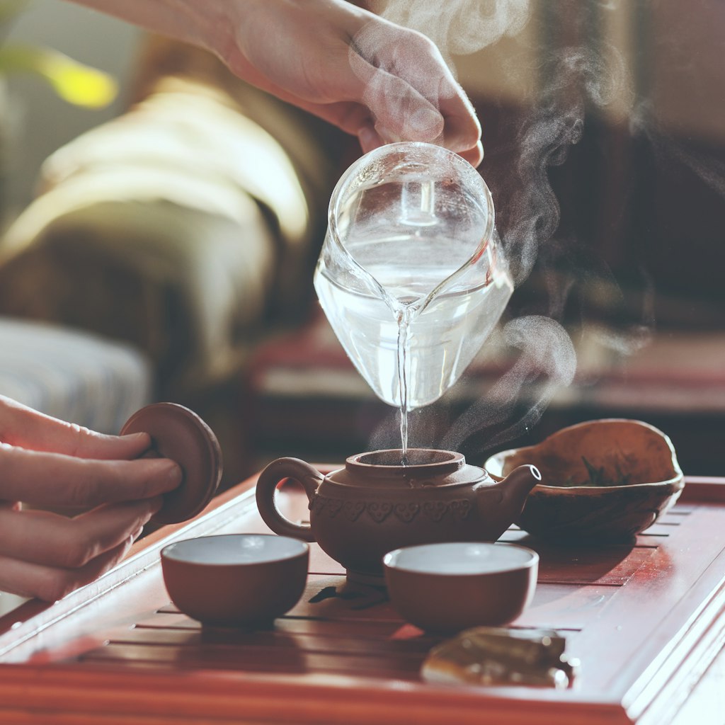 The tea ceremony. The woman pours hot water into the teapot with tea