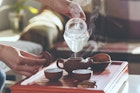 The tea ceremony. The woman pours hot water into the teapot with tea