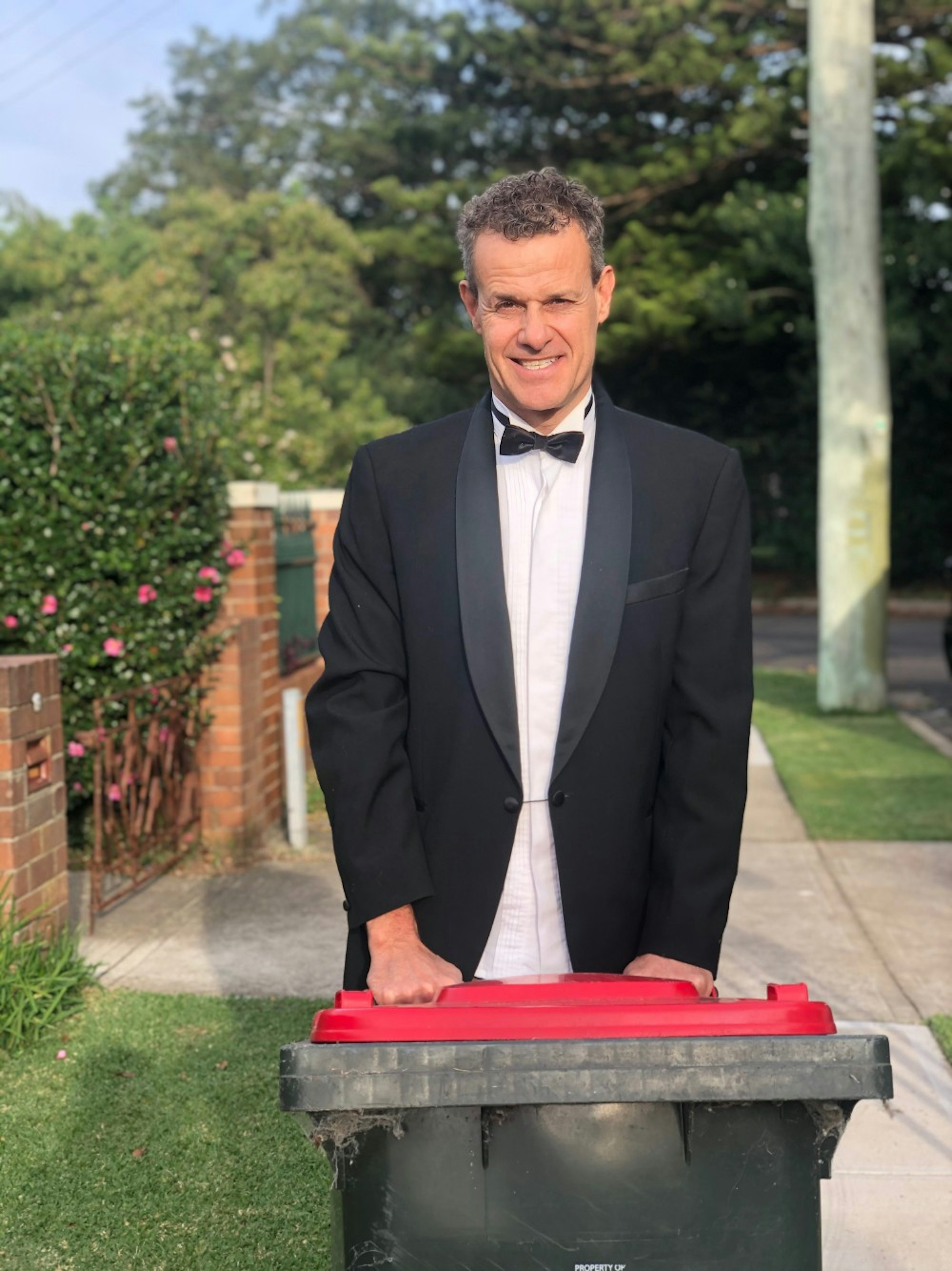 A man in a tuxedo bringing out his bin