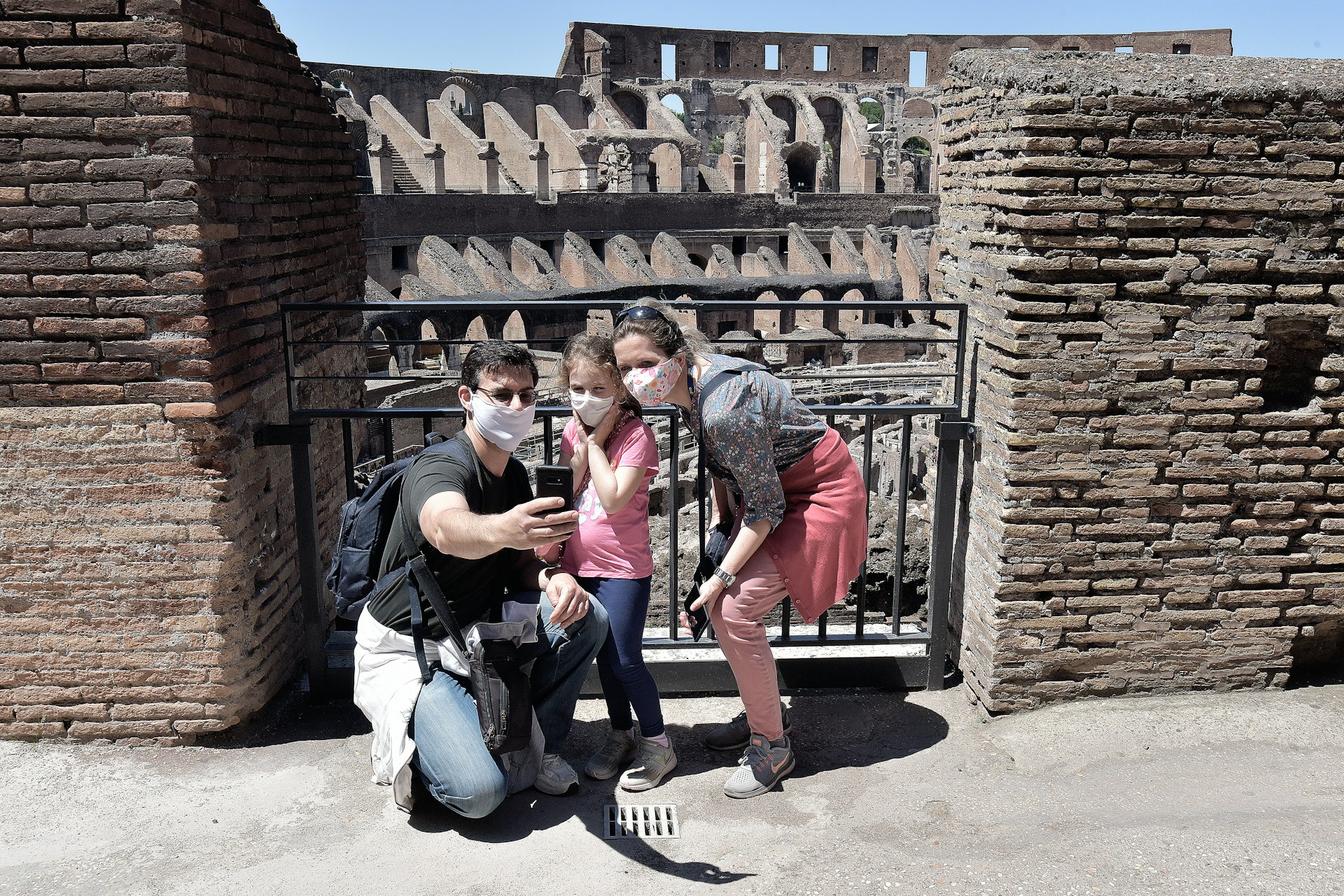 The Colosseum reopens to the public. A family of three, all wearing masks, pose for a selfie within the ancient monument