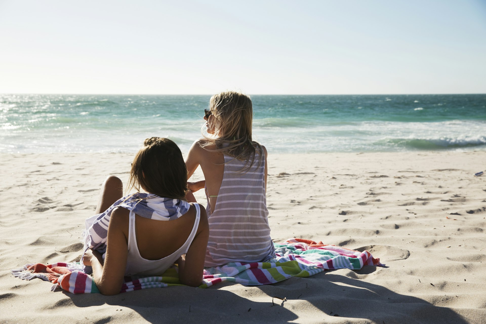 Group of friends and couple walking and hanging out on the beach, waring shorts and tops