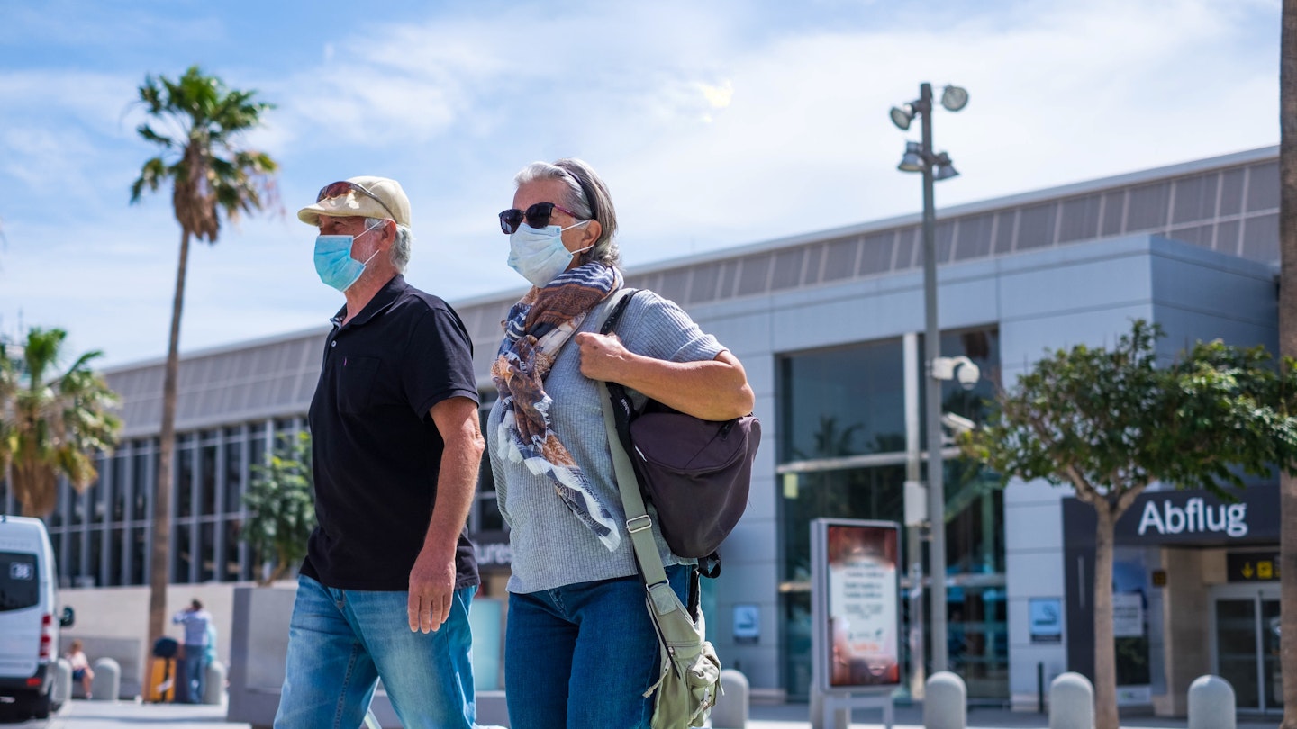 two senior walking with their baggage and wearing medical mask to prevent covid-19 or coronavirus or another type of virus or disease - safe travelers concept and lifestyle walking outdoor