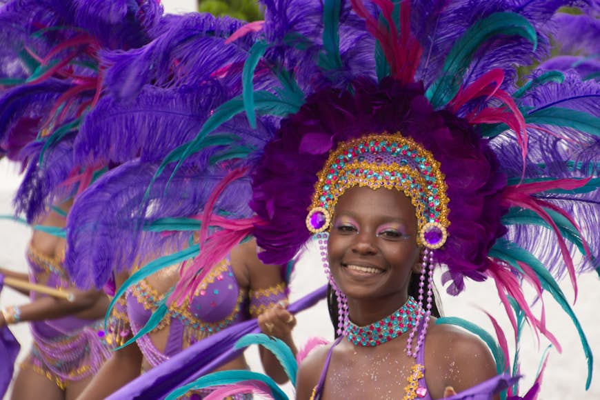 En leende kvinna i en lila befjädrad huvudbonad under karnevalen i St Thomas, USA Jungfruöarna, USA