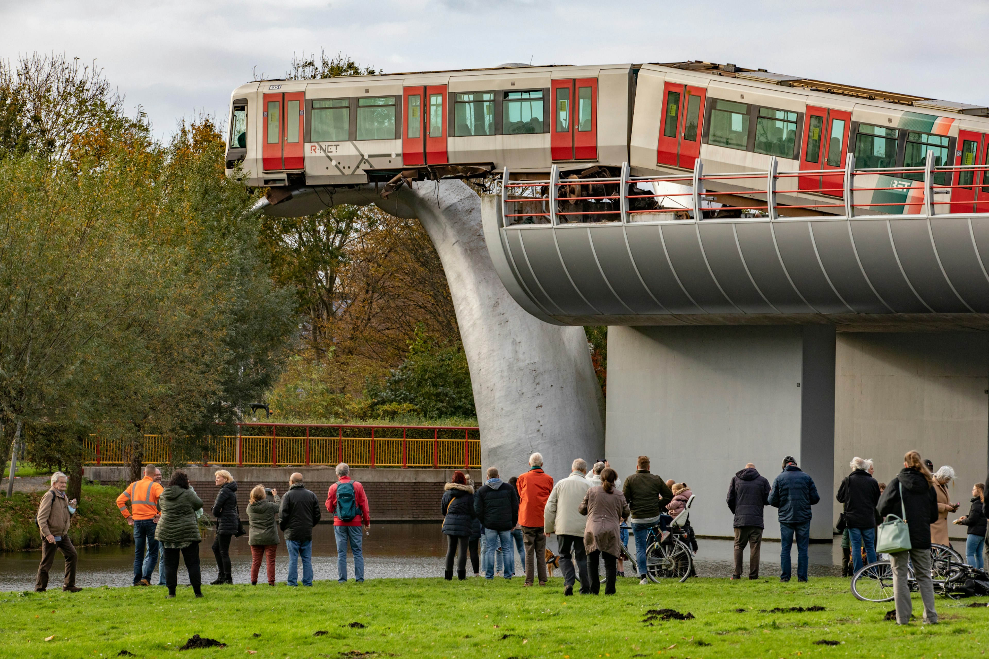 People looking at the train that the train that went off the track and landed on a whale tail