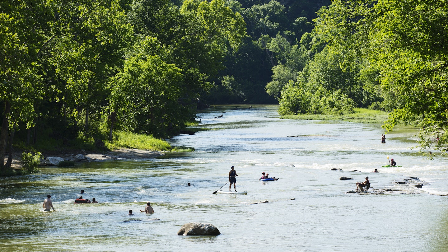 people play at the Whitewater park in Northwest Arkansas by swimming and paddle boarding and kayaking on the Illinois River