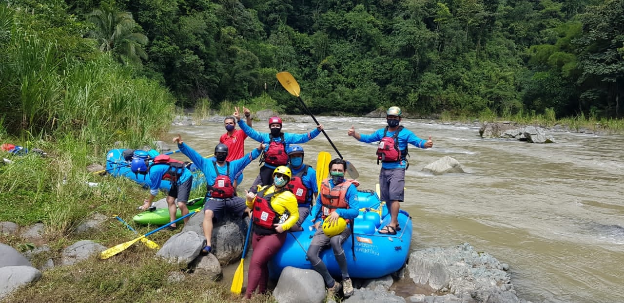 People posing next to inflatable rafts, with a river in the background