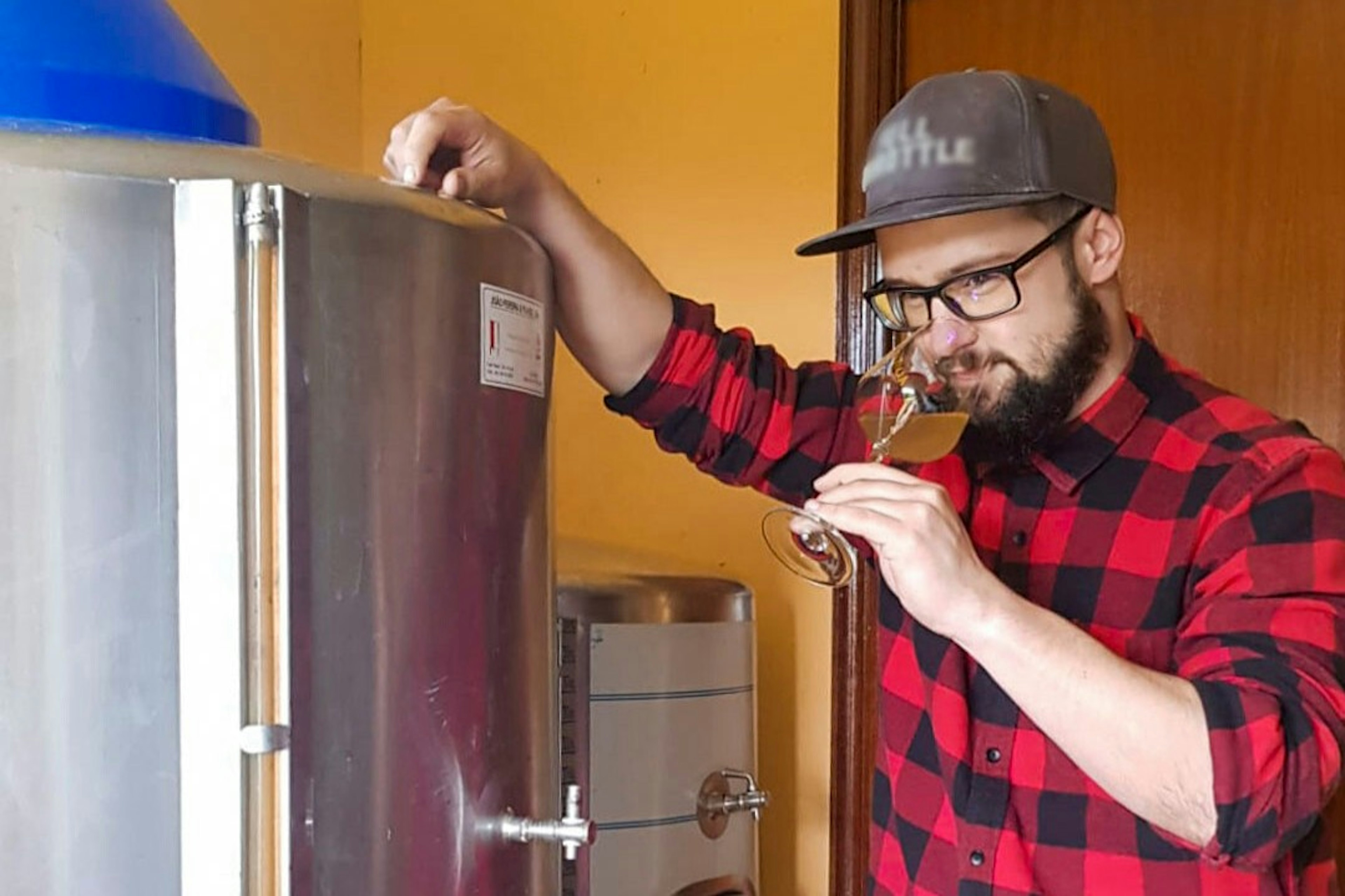 A man drinking wine standing by a fridge