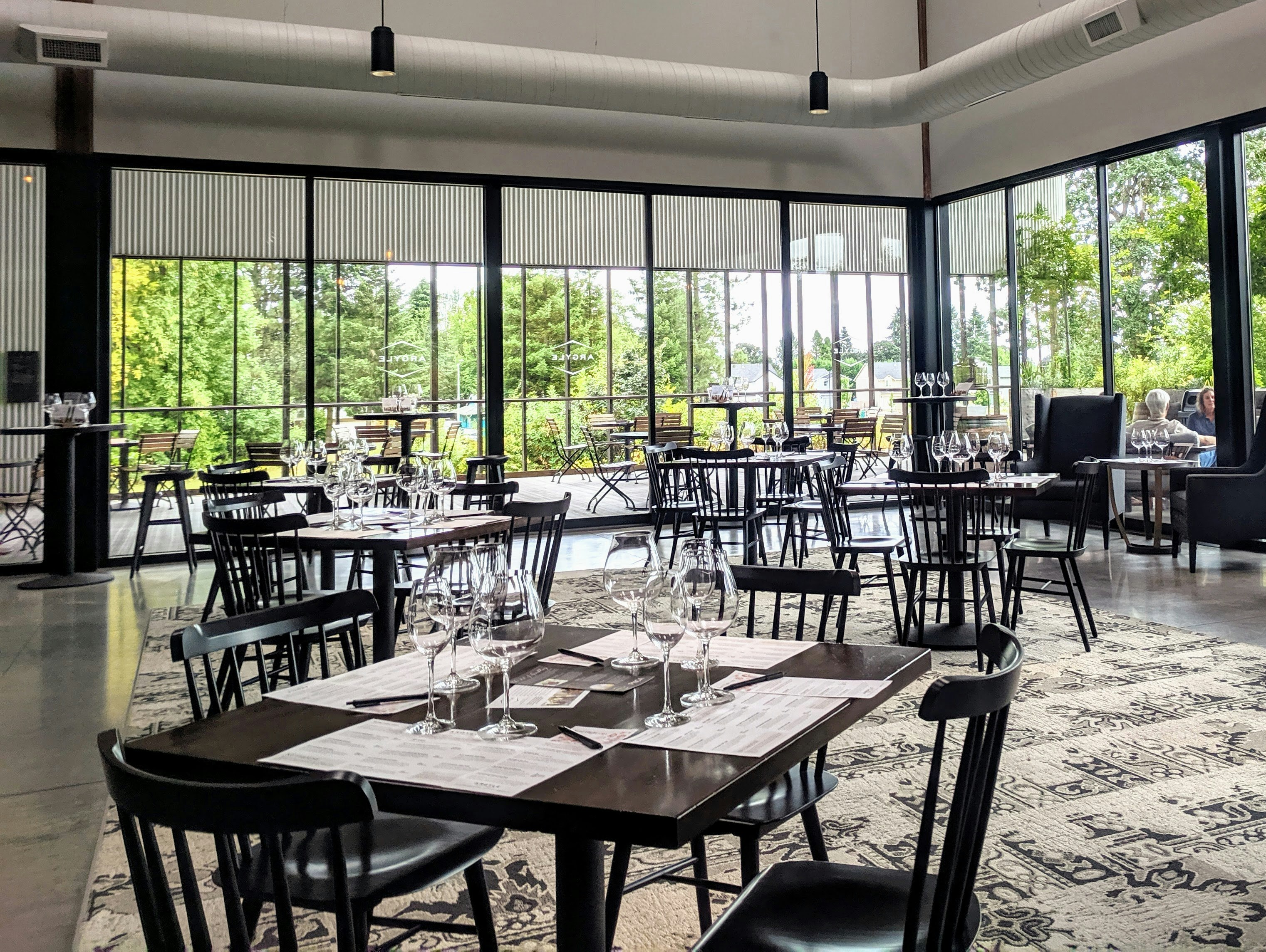 The interior of Argyle Winery in Willamette Valley Oregon is full of natural light and black turned wood chairs at dark brown four tops