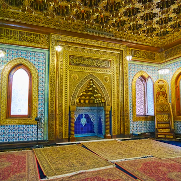 Cairo, Egypt - December 24, 2017: Mihrab of Manial Palace mosque decorated with intricate golden patterns on carved wood, muqarnas in arch, bright blue tiles inside of niche, on December 24 in Cairo