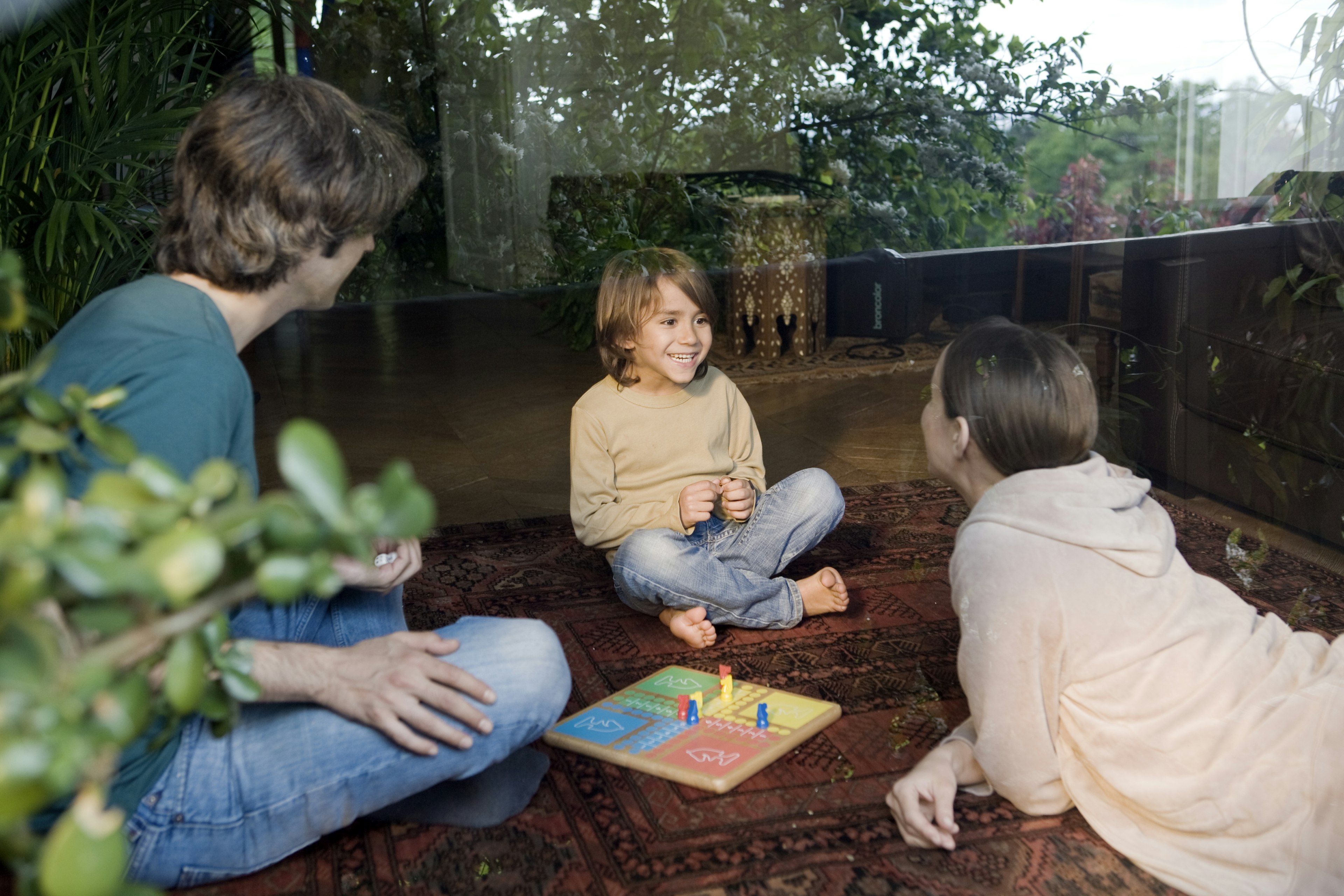 family plays board game, seen from outside