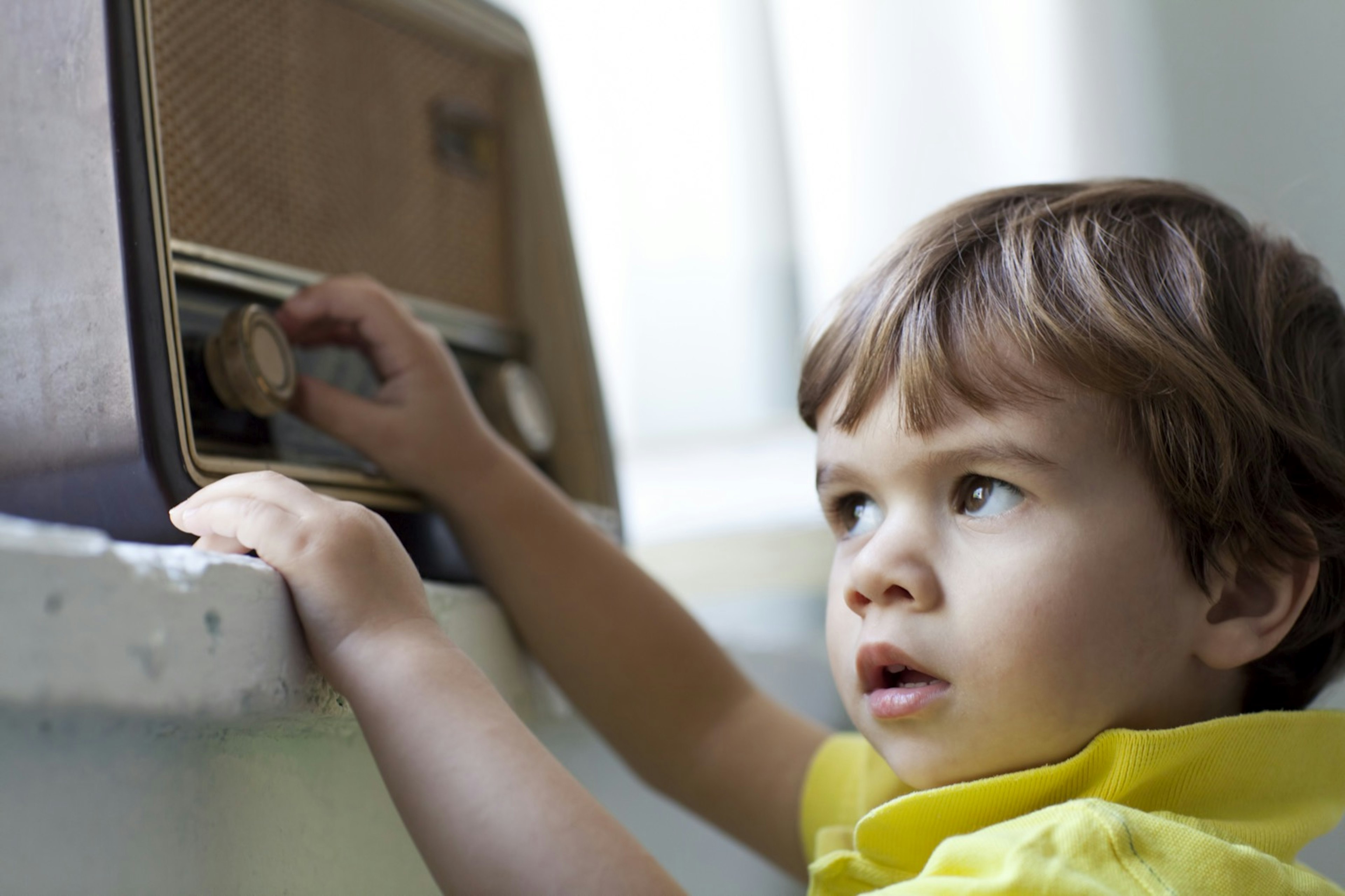 Small boy listening music from an old radio