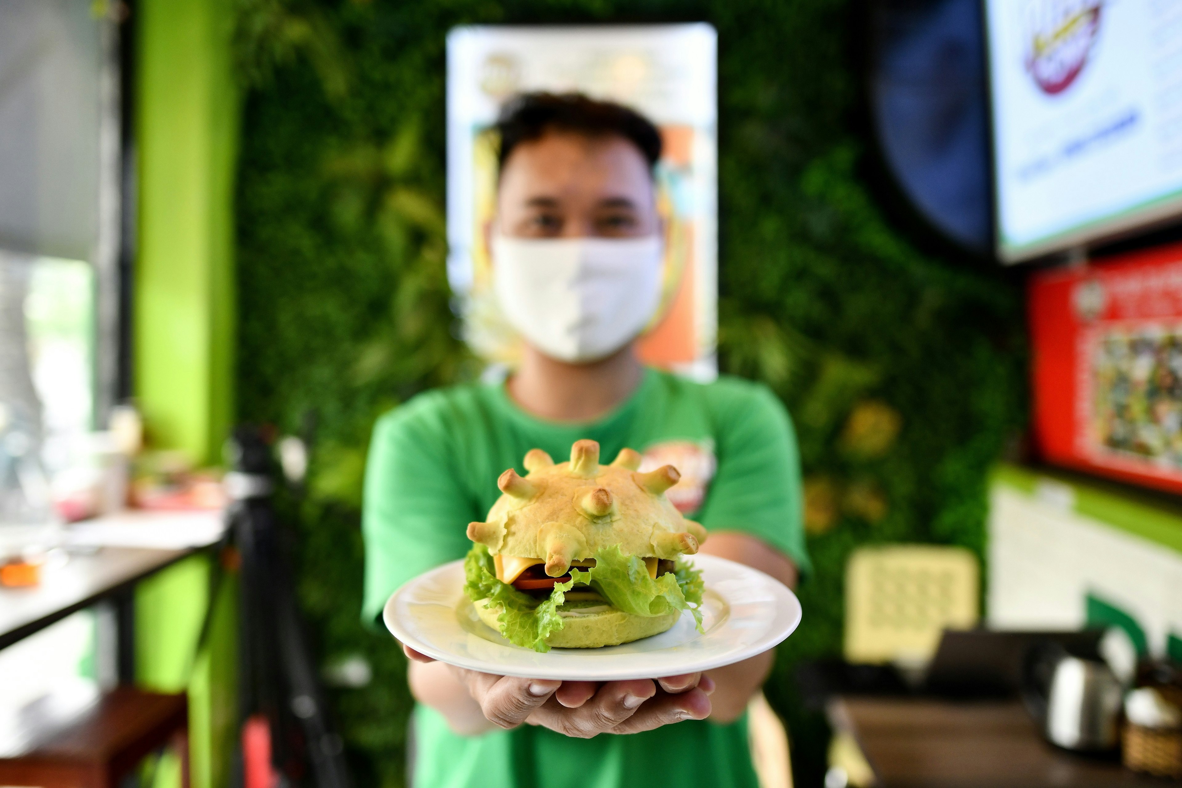 Pizza Home restaurant owner Hoang Tung poses with a coronavirus-themed burger in Hanoi on March 26, 2020, amid restrictions being put in place to contain the spread of the COVID-19 coronavirus.