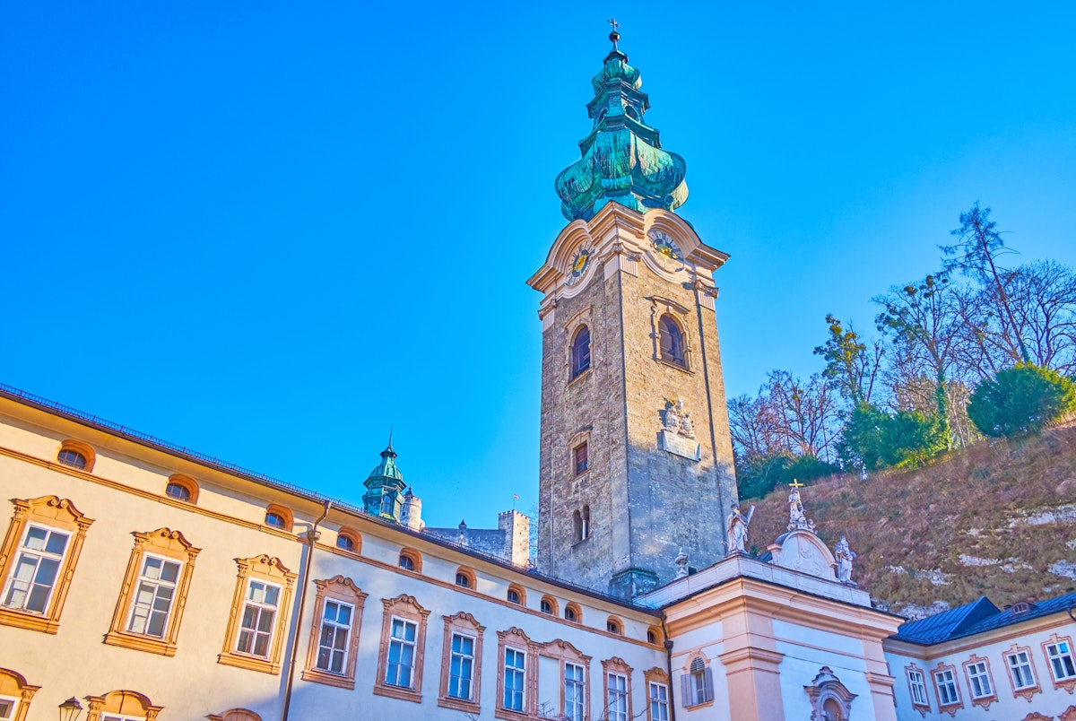 The mighty bell tower of the Collegiate Church of Abbey of St.Peter complex with greenery of Monchsberg hill on the background, Salzburg, Austria; Shutterstock ID 1478477327; Your name (First / Last): Lauren Vastine; GL account no.: 65050; Netsuite department name: Online Editorial; Full Product or Project name including edition: BiT2020 Imagery