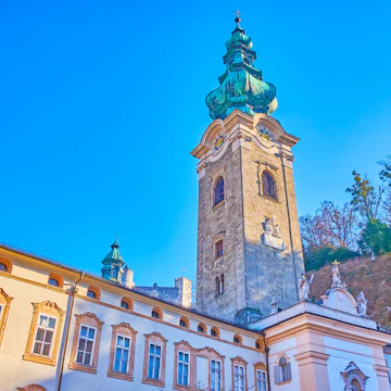 The mighty bell tower of the Collegiate Church of Abbey of St.Peter complex with greenery of Monchsberg hill on the background, Salzburg, Austria; Shutterstock ID 1478477327; Your name (First / Last): Lauren Vastine; GL account no.: 65050; Netsuite department name: Online Editorial; Full Product or Project name including edition: BiT2020 Imagery