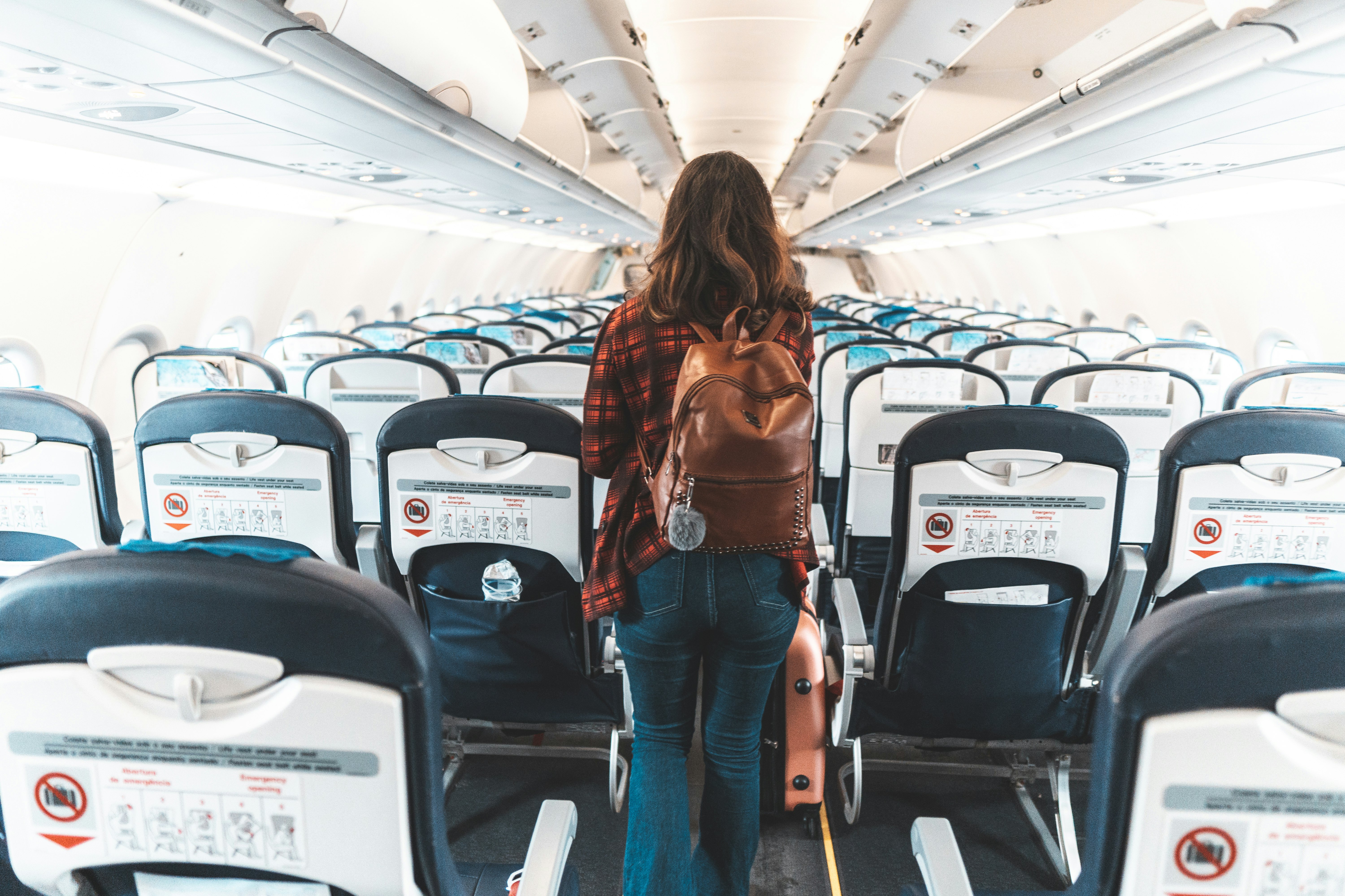 A woman walking down the aisle of an airplane