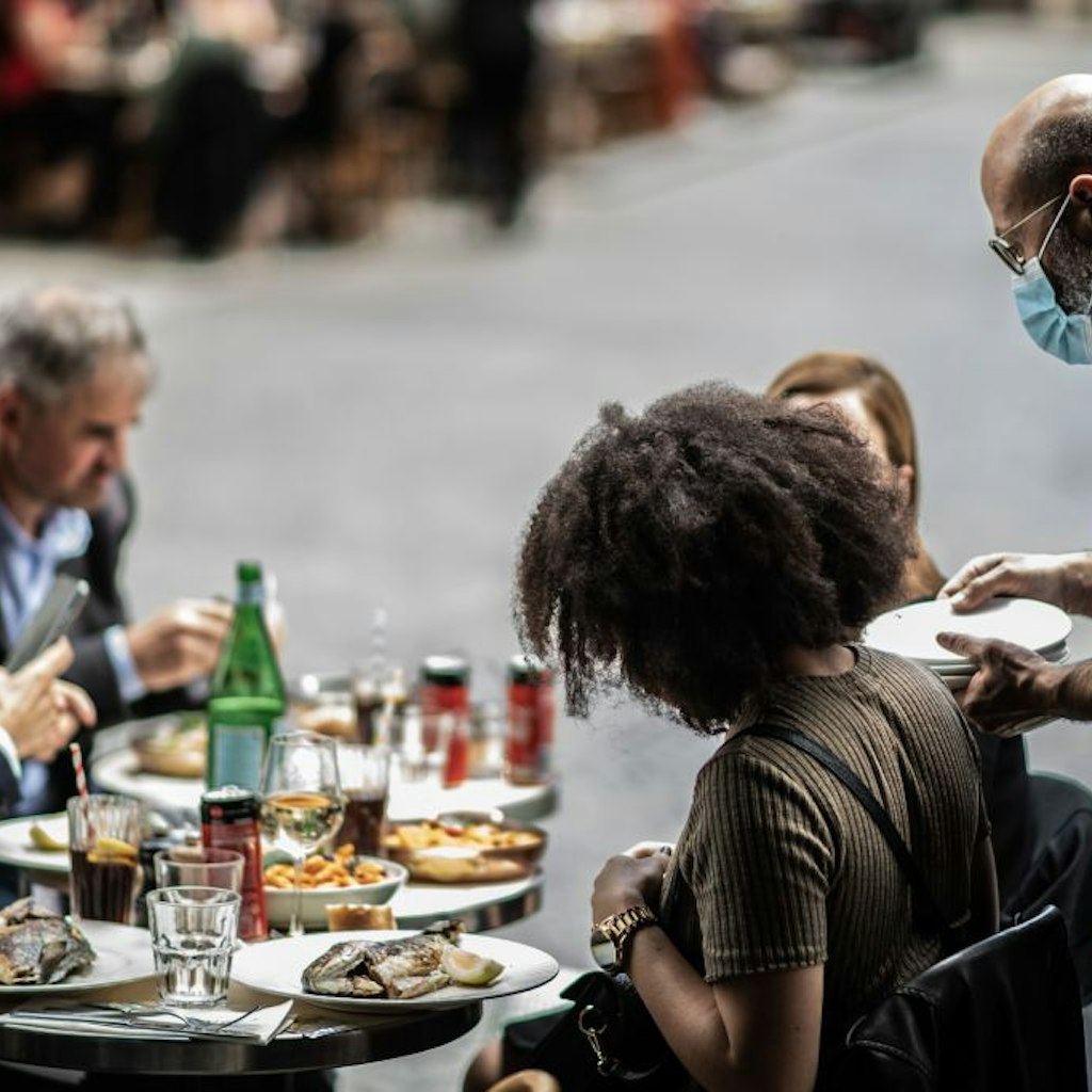 A waiter serves customers at a terrace of a restaurant in Paris, on June 15, 2020, as cafes and restaurants are allowed to serve customers inside, as well as on terraces, as part of the easing of lockdown measures taken to curb the spread of the COVID-19 pandemic, caused by the novel coronavirus. (Photo by Martin BUREAU / AFP) (Photo by MARTIN BUREAU/AFP via Getty Images)
